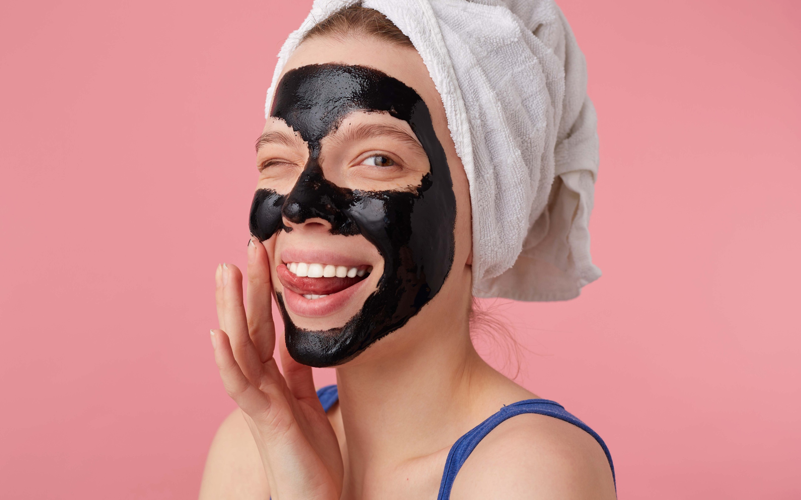 Смешная молодая девушка с черной косметической маской на лице 