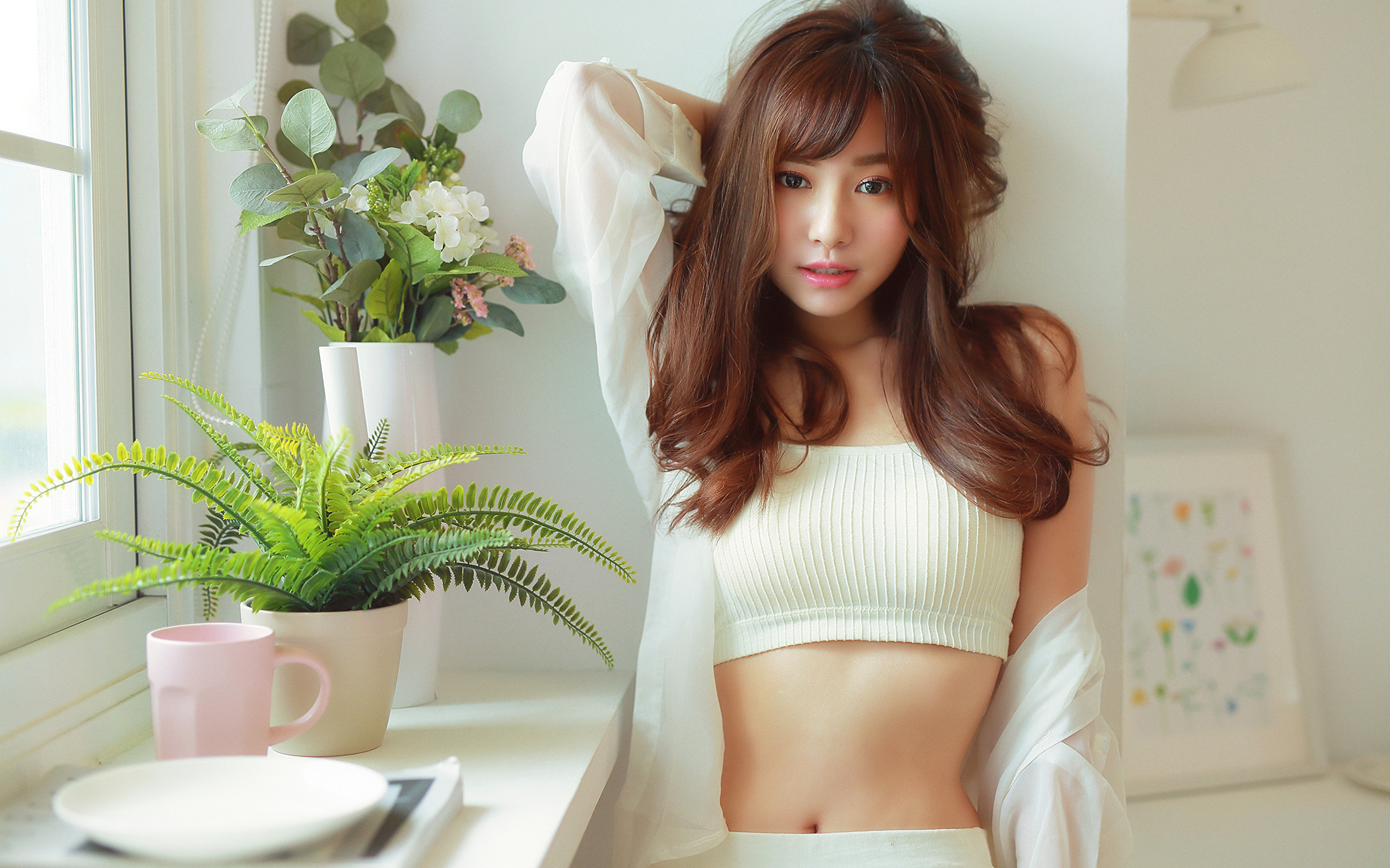 Нежная девушка азиатка стоит у окна