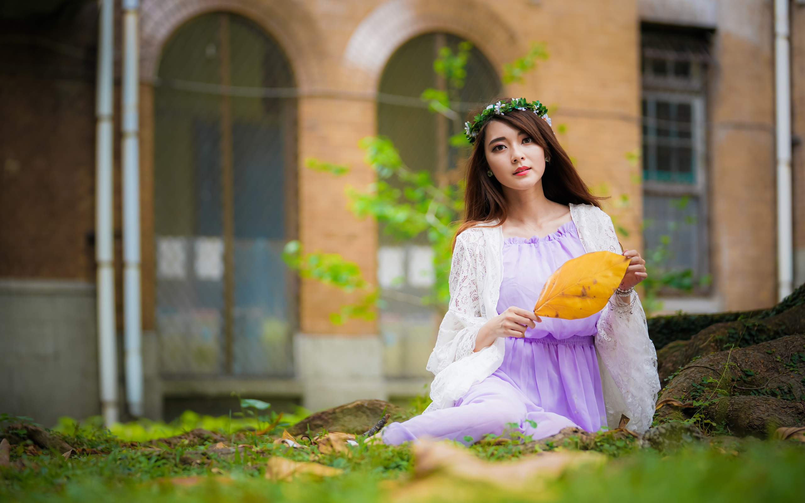 Девушка в красивом платье сидит на траве 