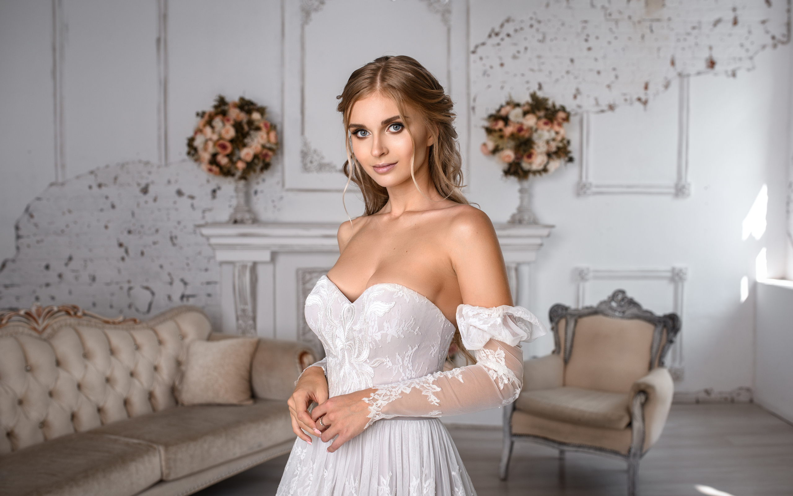 Милая девушка в свадебном платье в комнате с диваном
