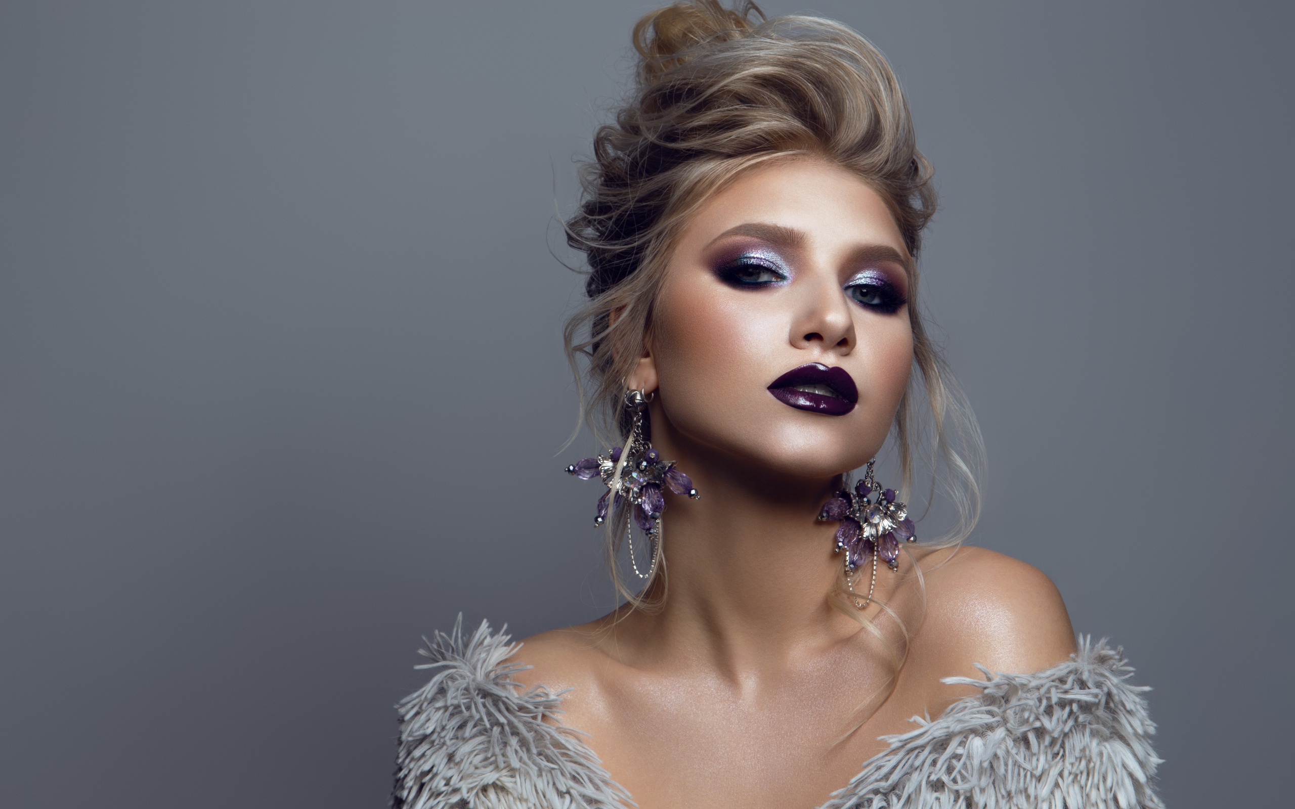 Эффектная девушка с ярким макияжем на сером фоне