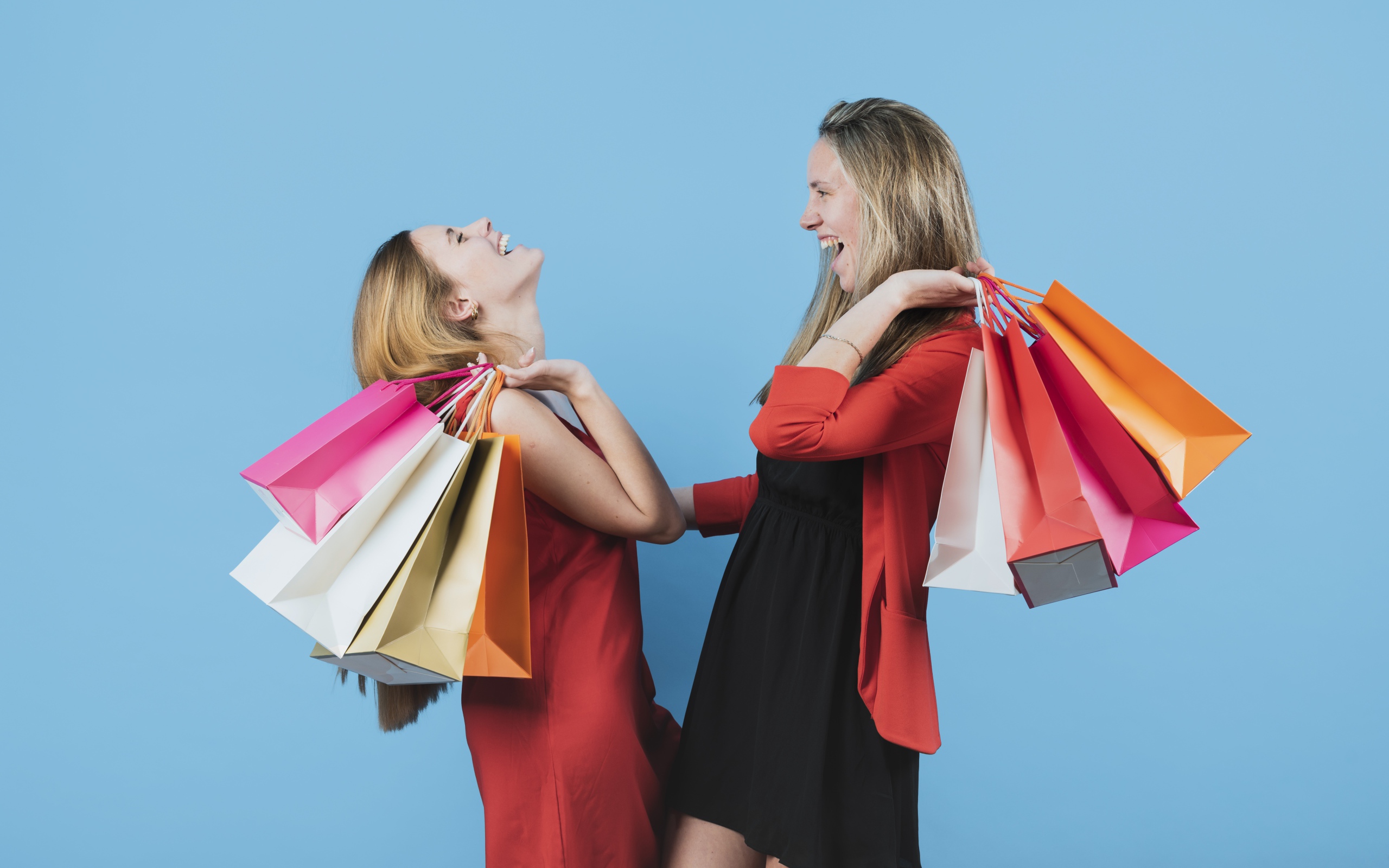 Две девушки с покупками на голубом фоне
