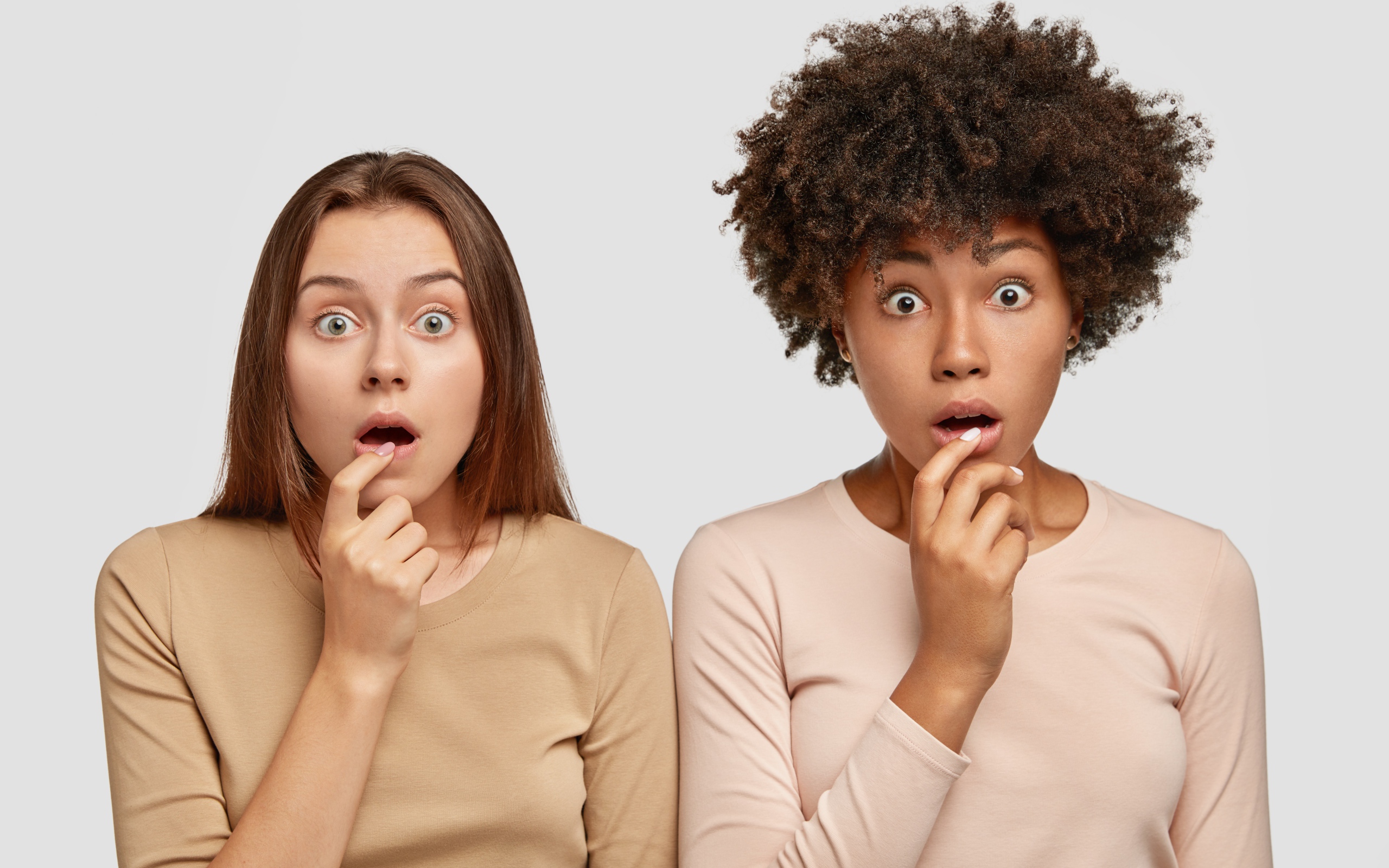 Две удивленные девушки на сером фоне 
