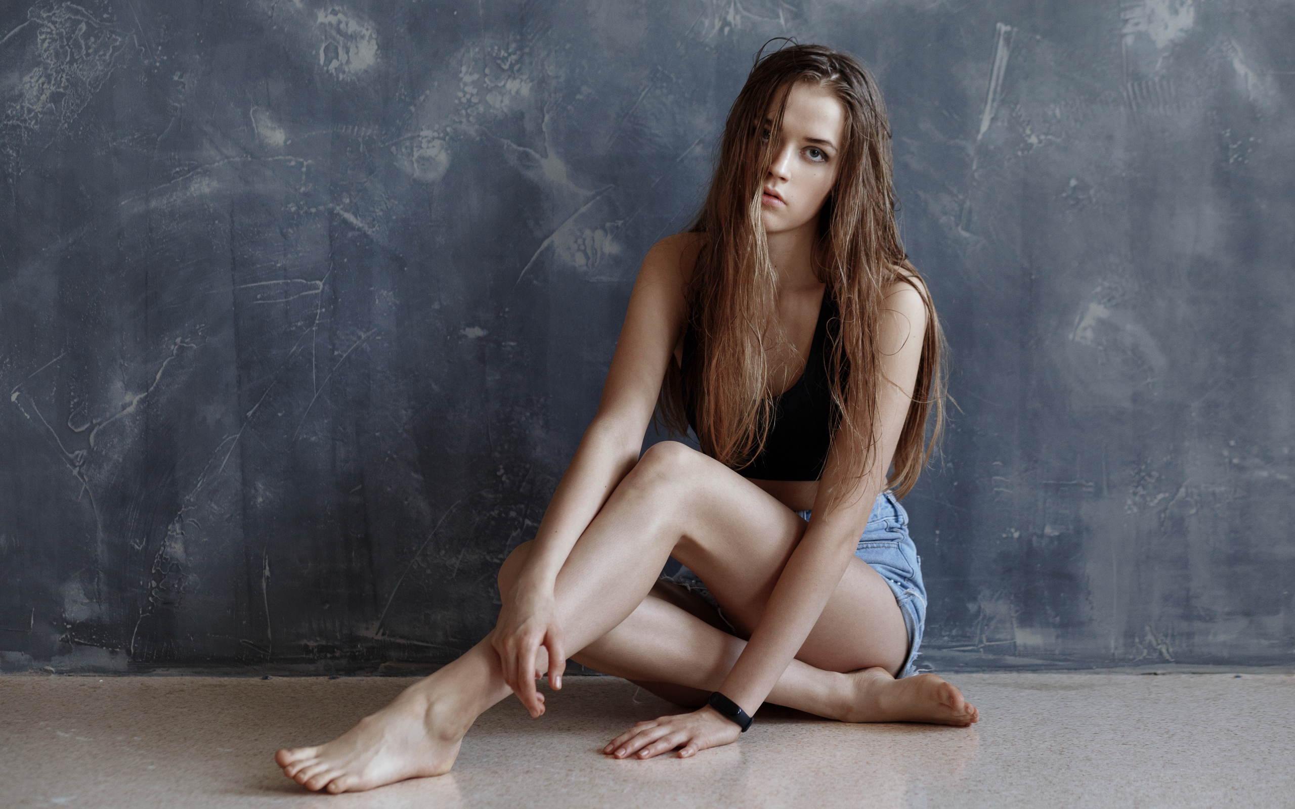 Молодая девушка с мокрыми волосами сидит у стены 