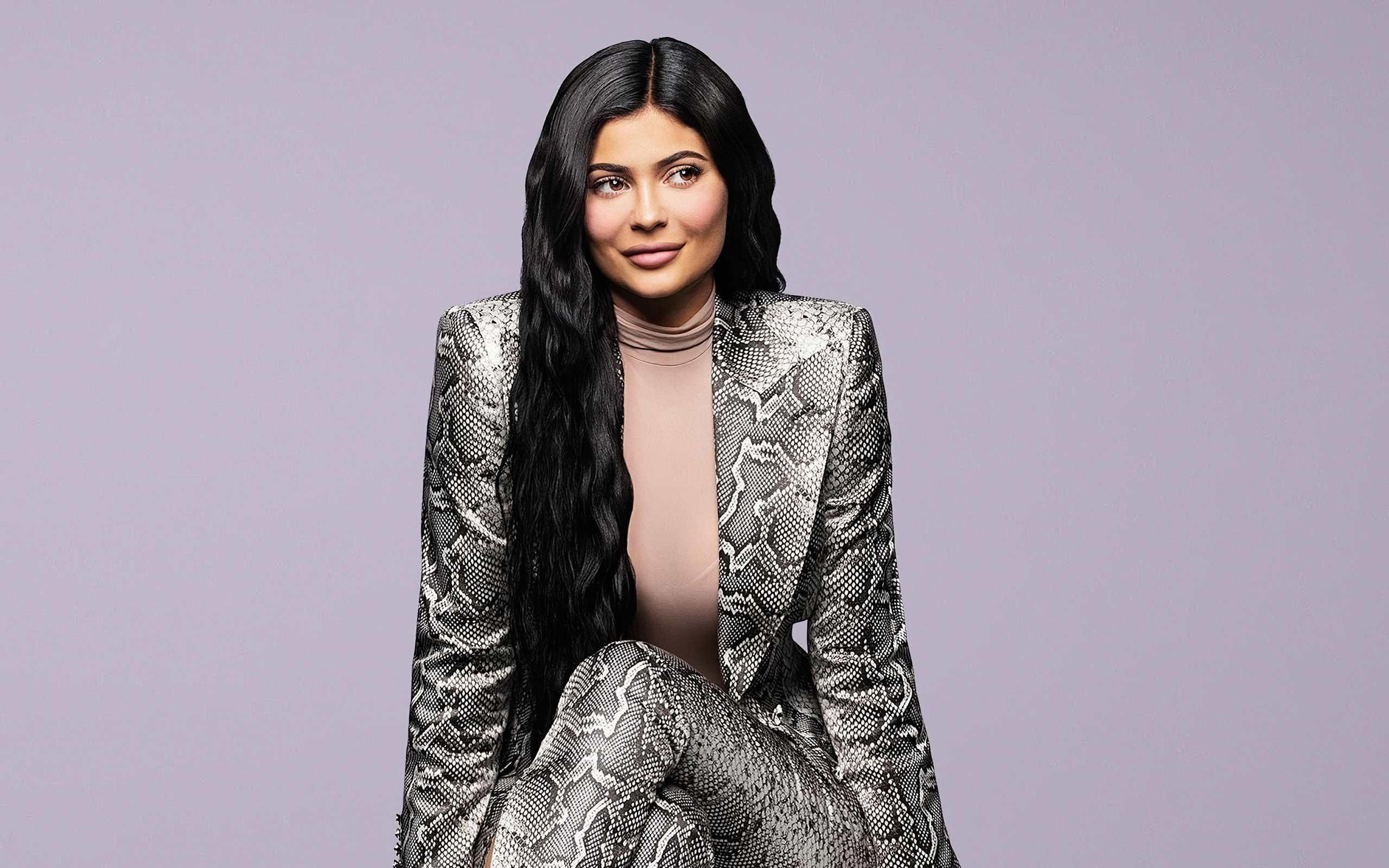 Длинноволосая модель Кайли Дженнер в костюме на сером фоне