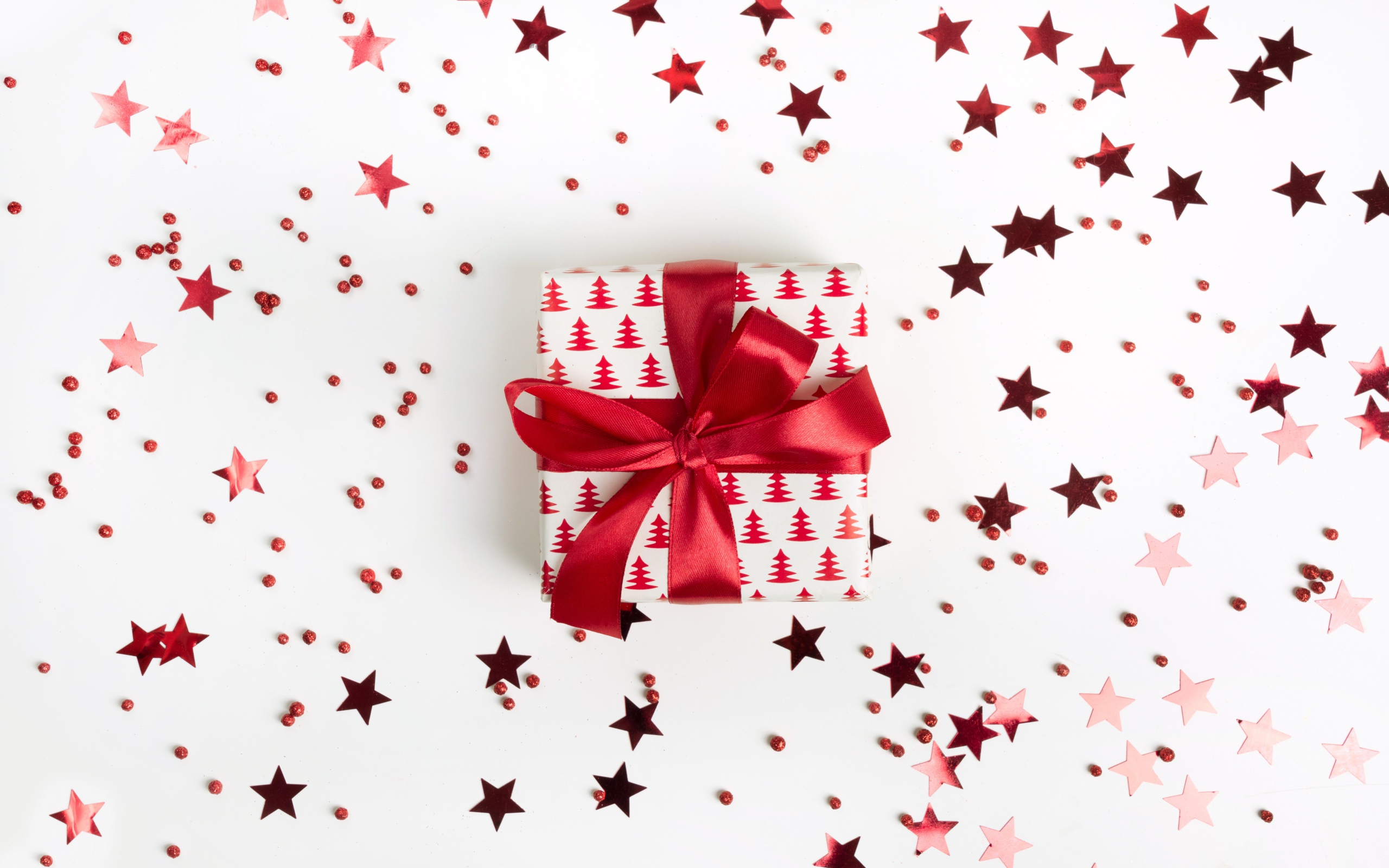 Подарок с красным бантом на белом фоне со звездочками