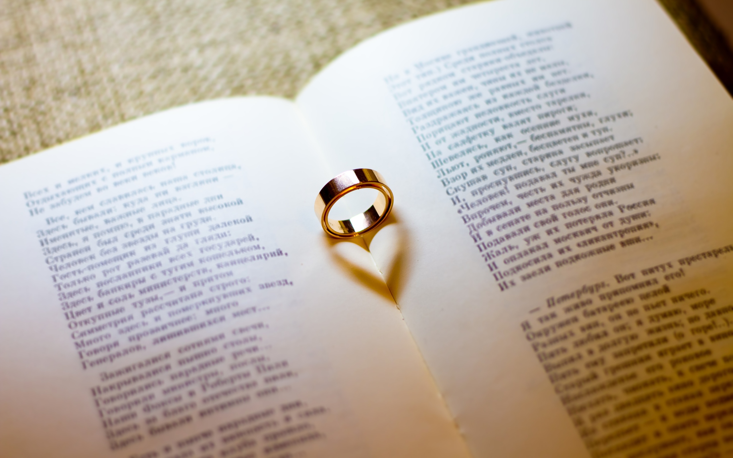 Золотое обручальное кольцо лежит на открытой книге
