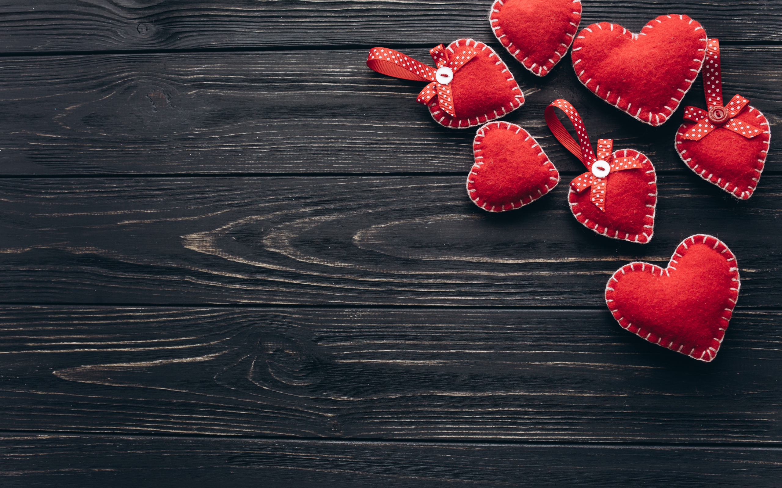 Много красных сердечек из фетра на деревянном столе