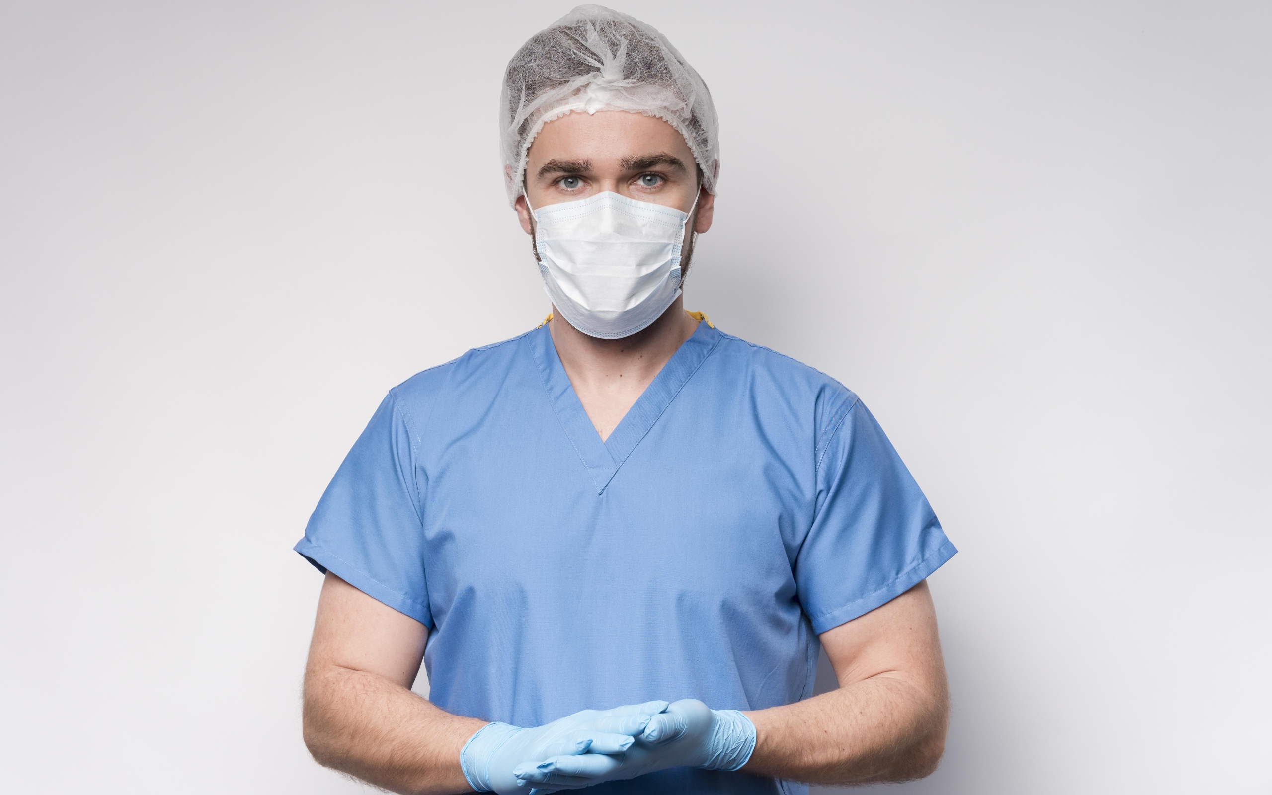 Мужчина врач в маске и перчатках на сером фоне