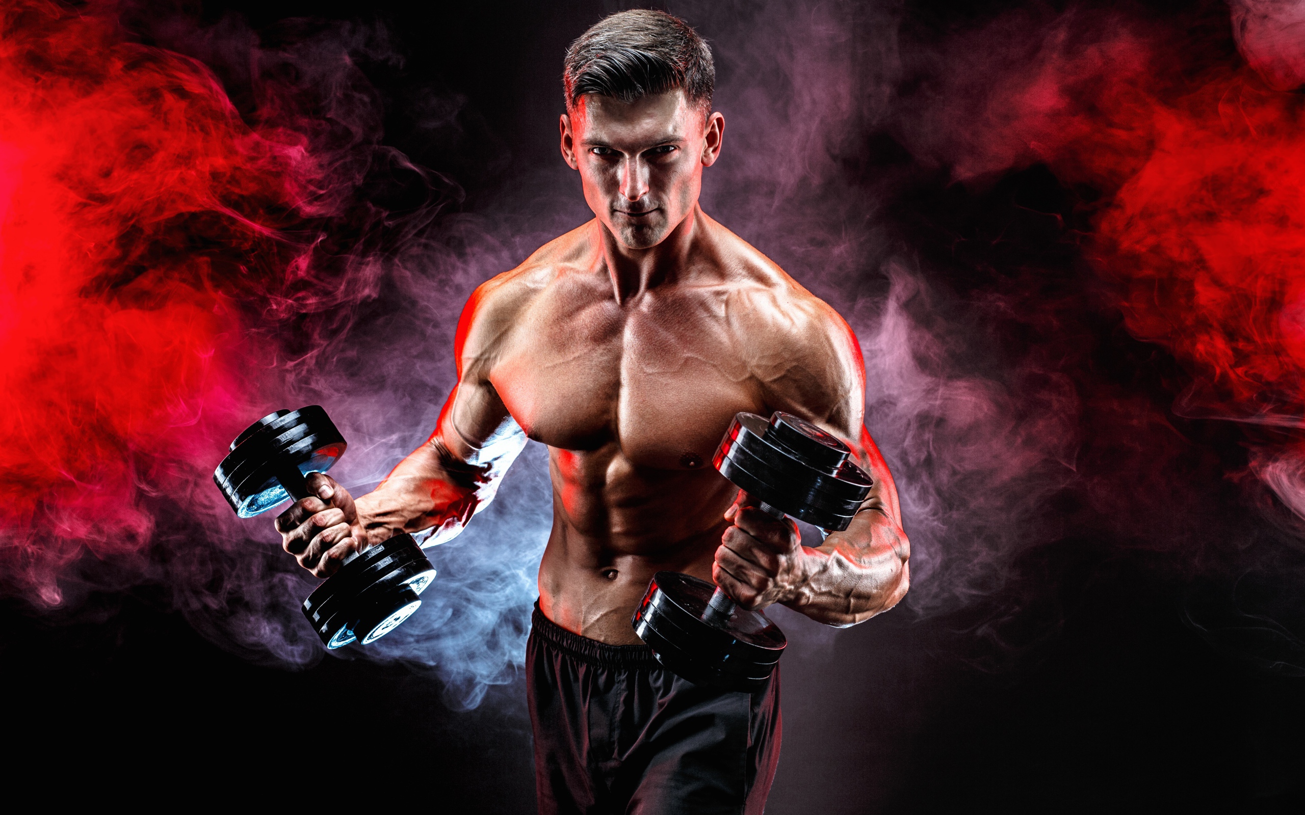 Мускулистый мужчина с гантелями в руках на черном фоне с дымом