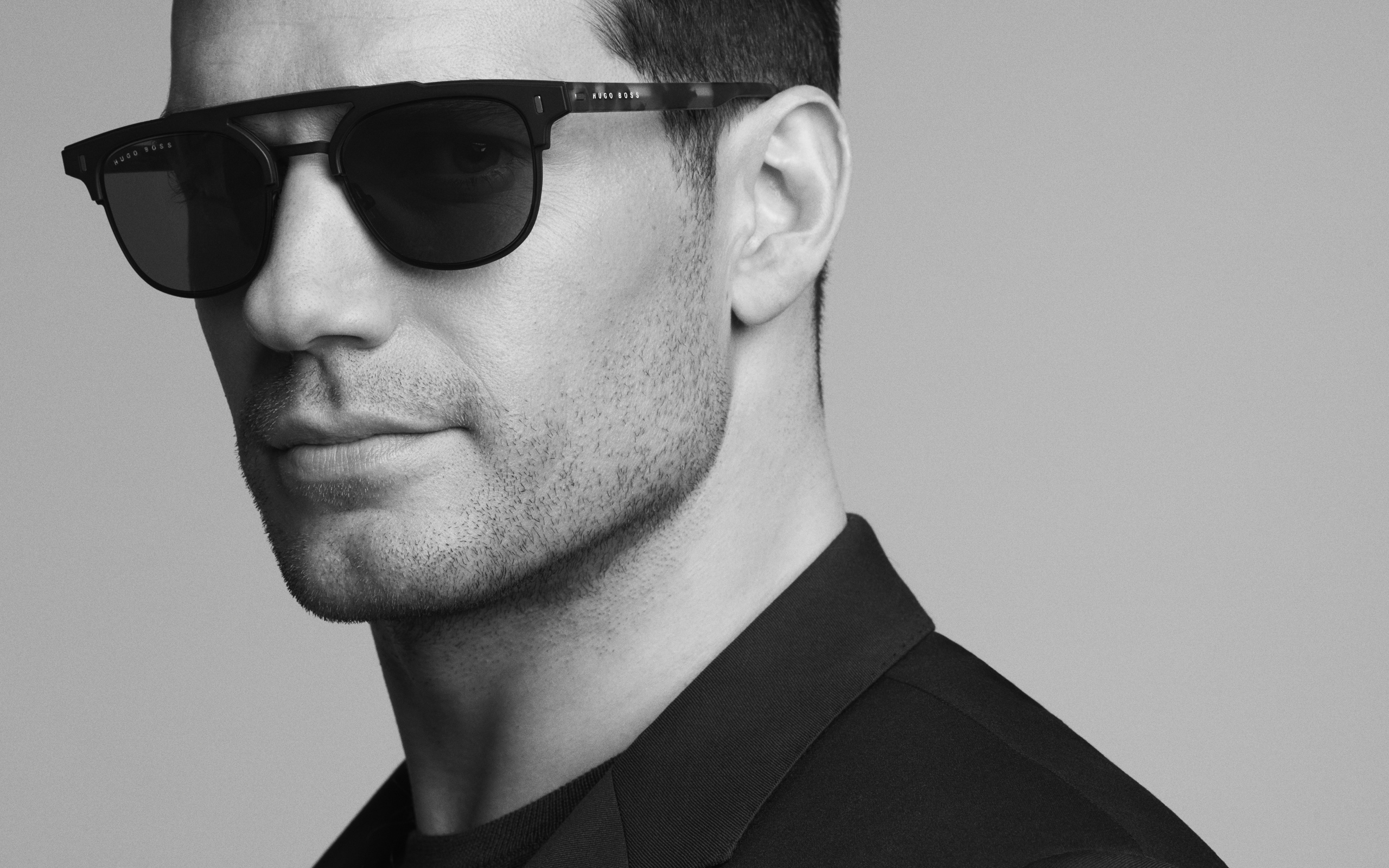 Актер Генри Кавилл в черных очках на сером фоне