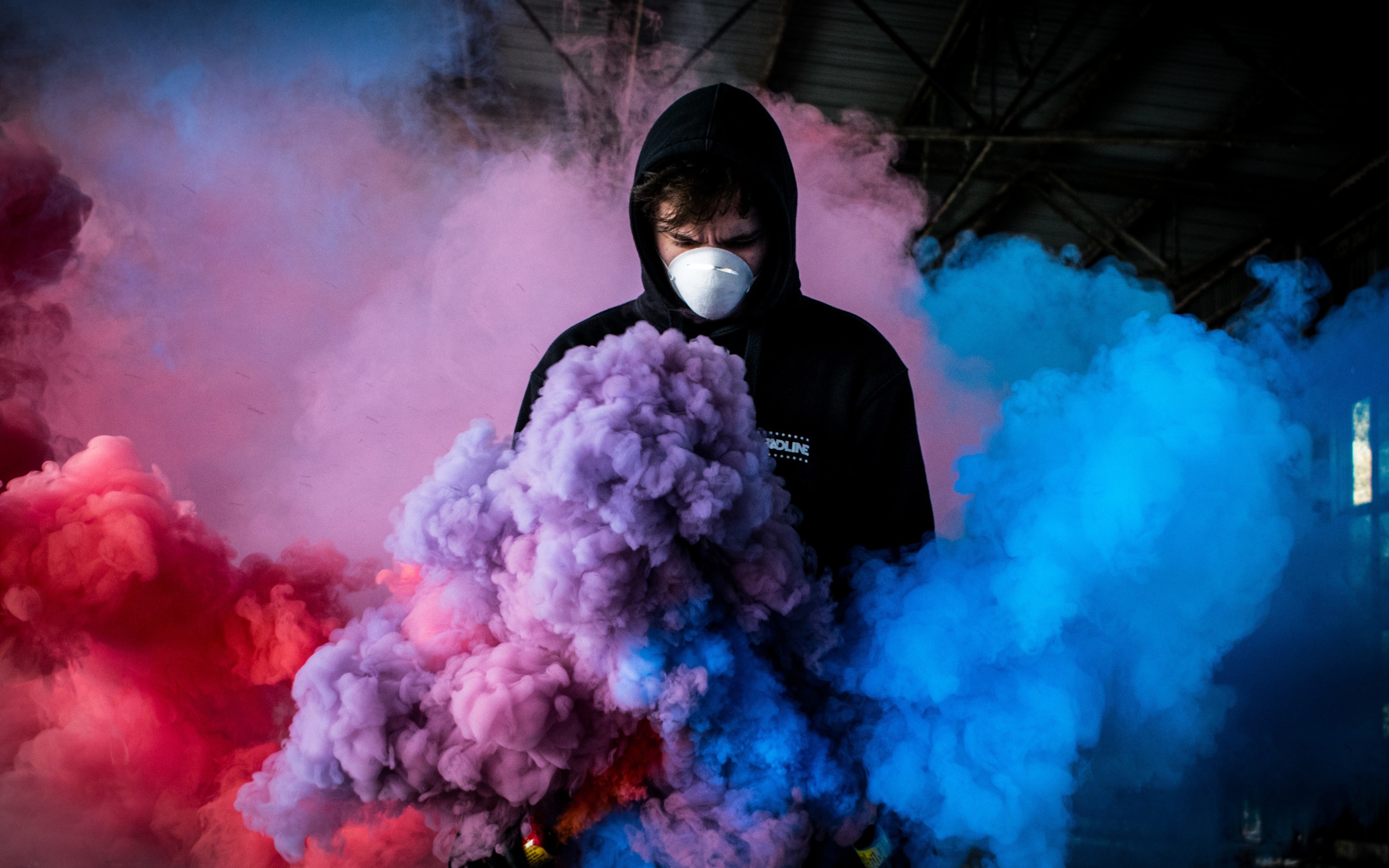 Мужчина в маске с разноцветными дымовыми шашками