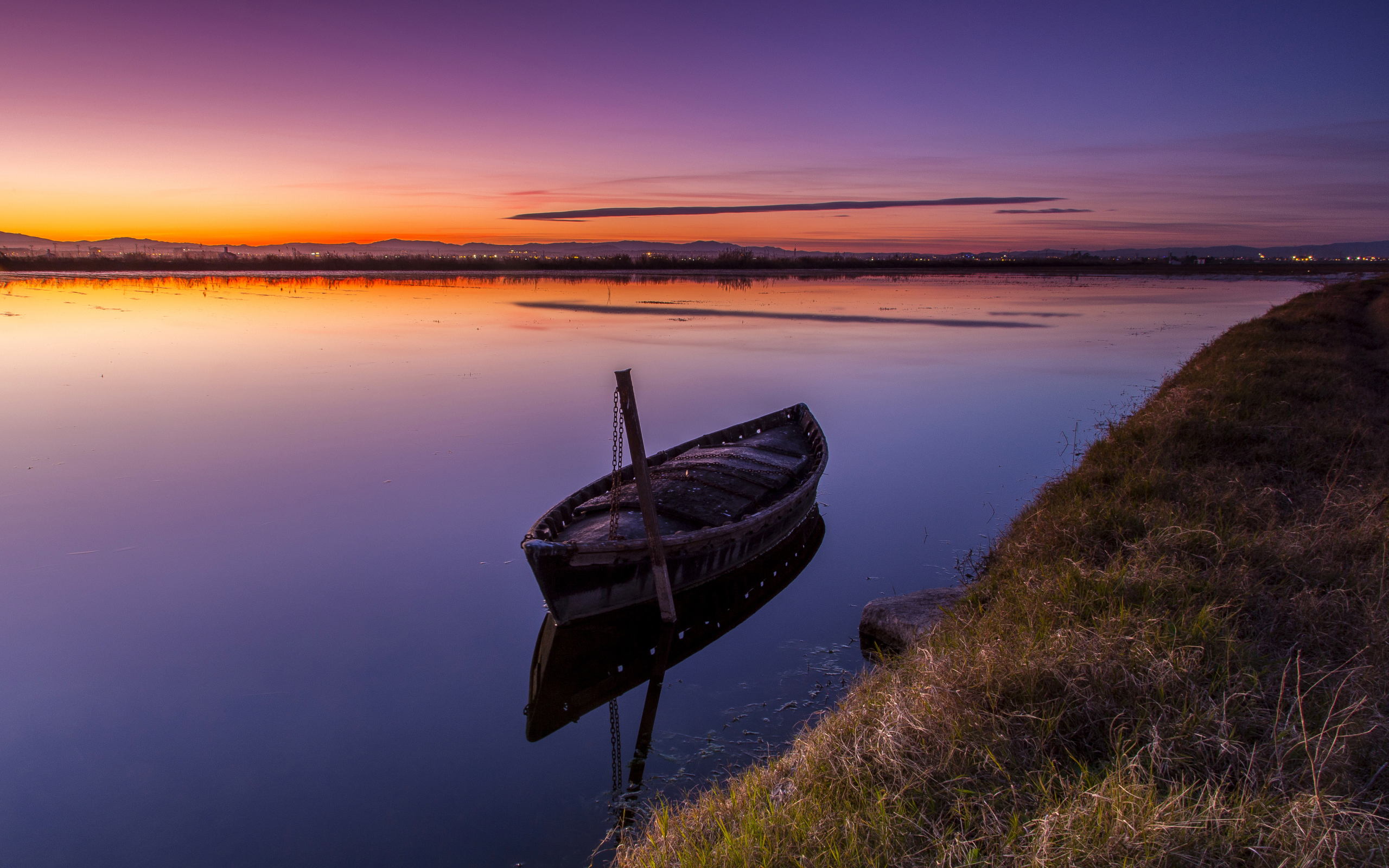 Старая лодка стоит в воде на закате солнца 