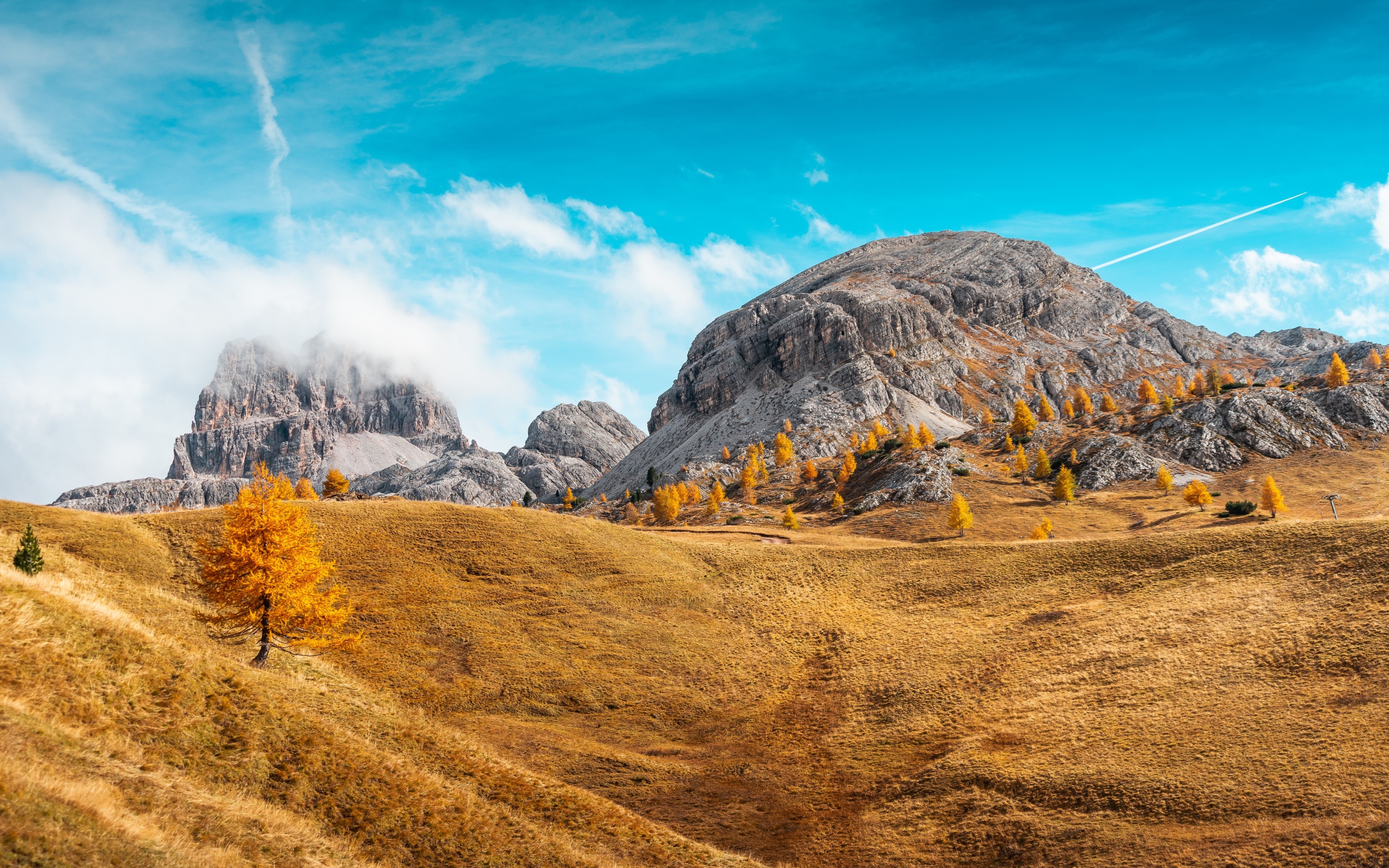 Холмы с сухой травой у гор под голубым небом