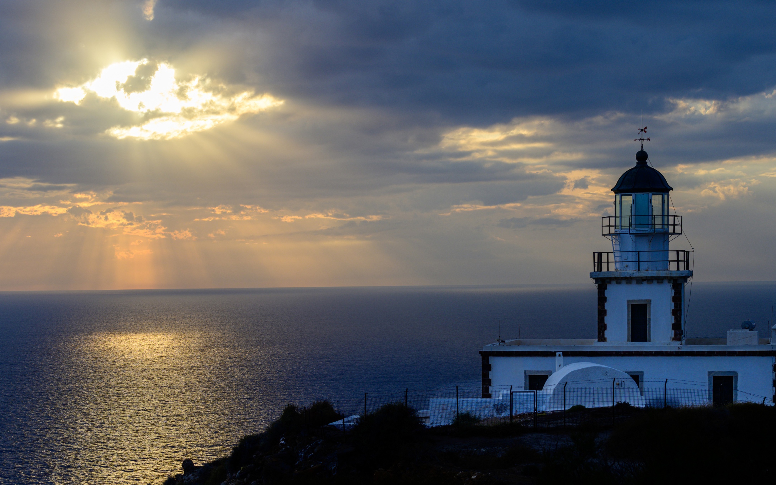 Белый маяк на берегу в лучах солнца у моря 