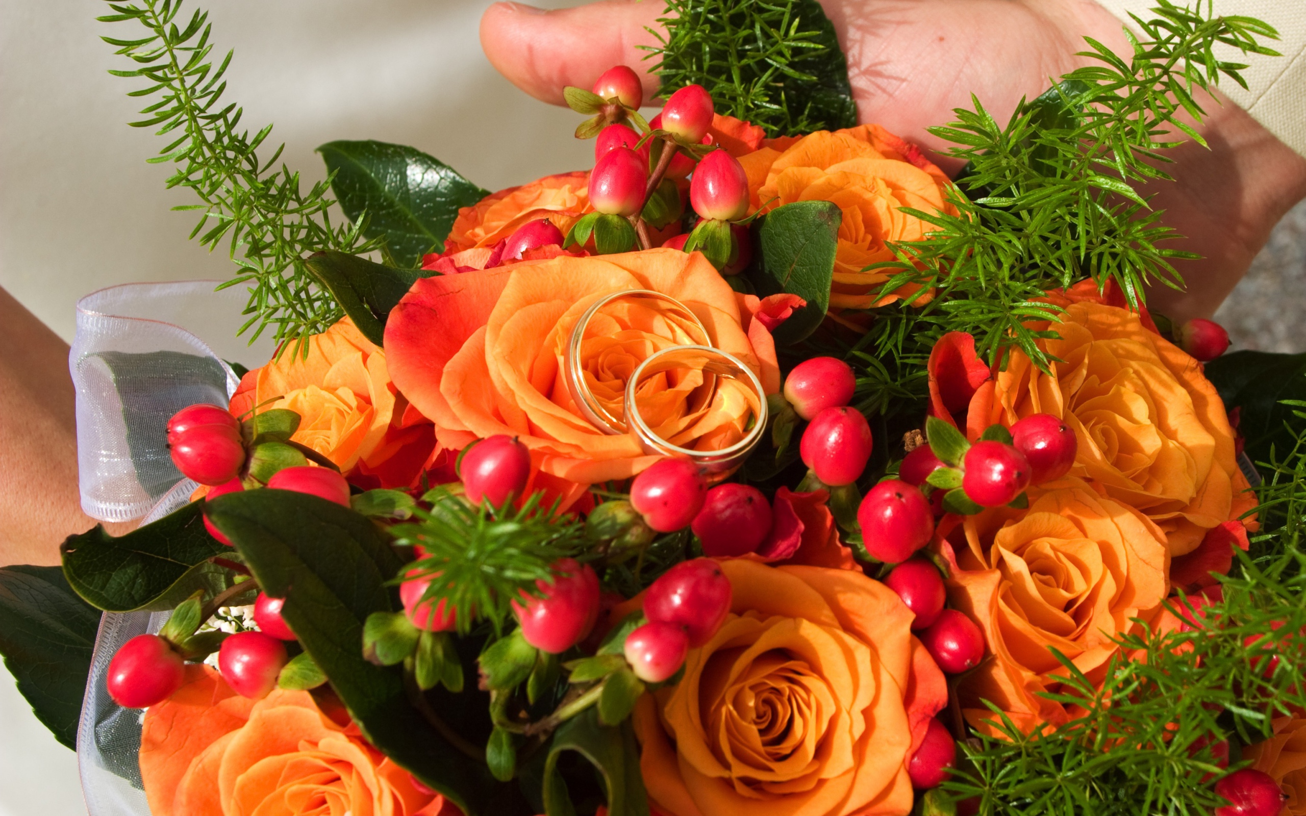 Букет оранжевых роз с красными ягодами и обручальными кольцами