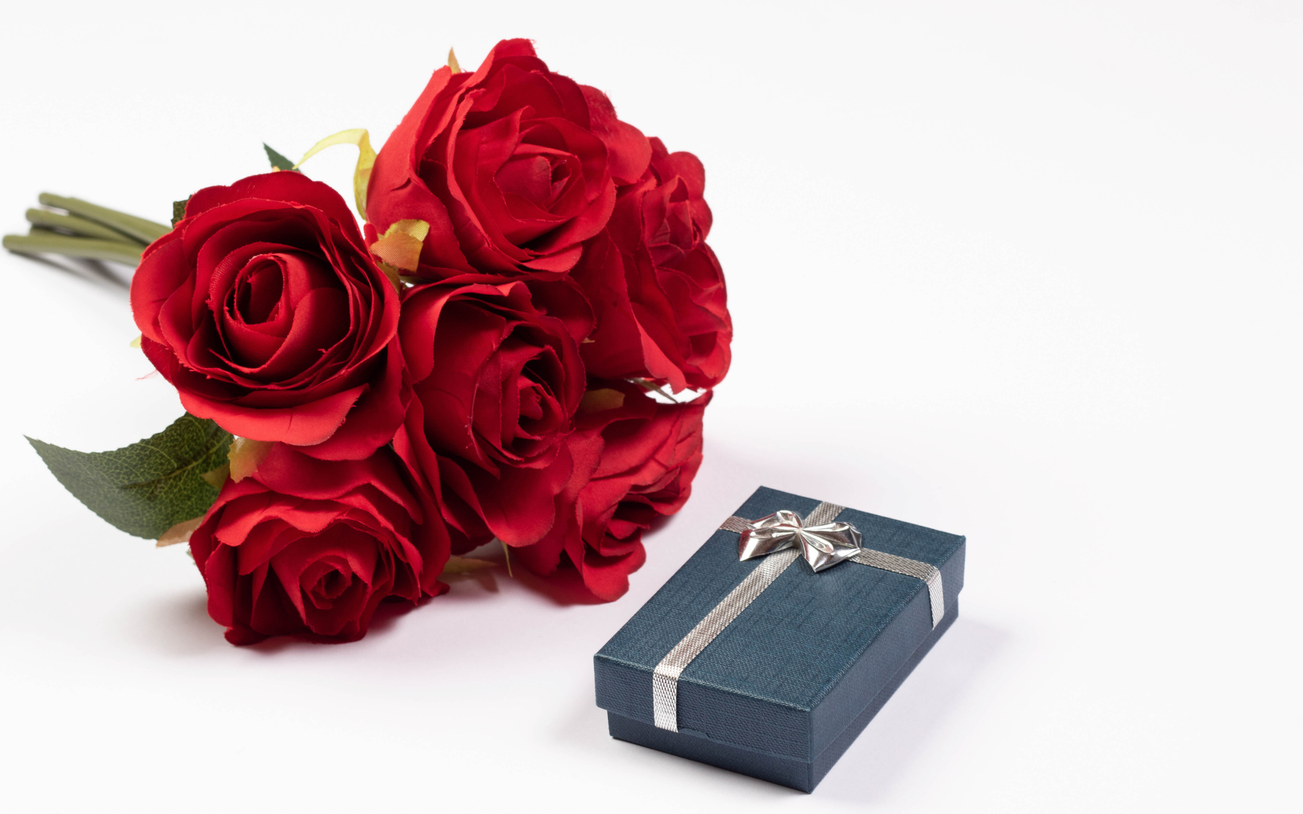 Букет красных искусственных роз с подарком на белом фоне