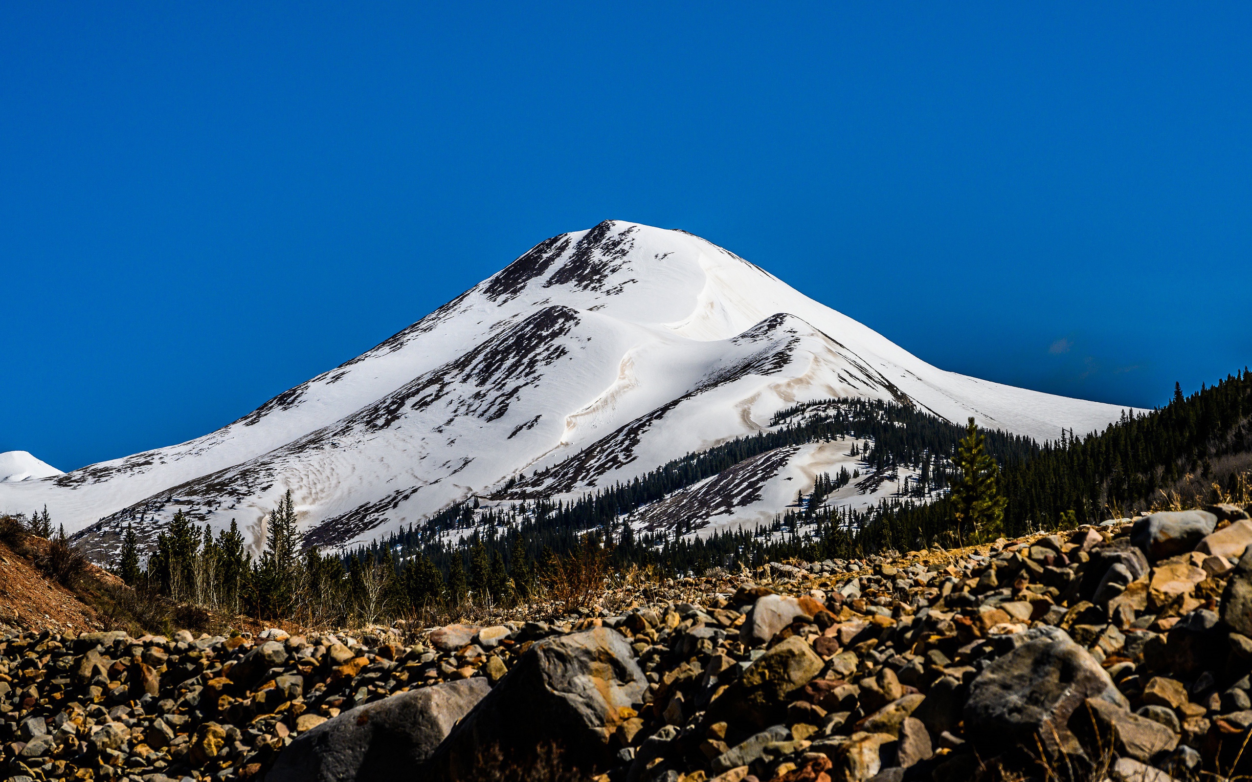Высокая заснеженная гора под голубым небом