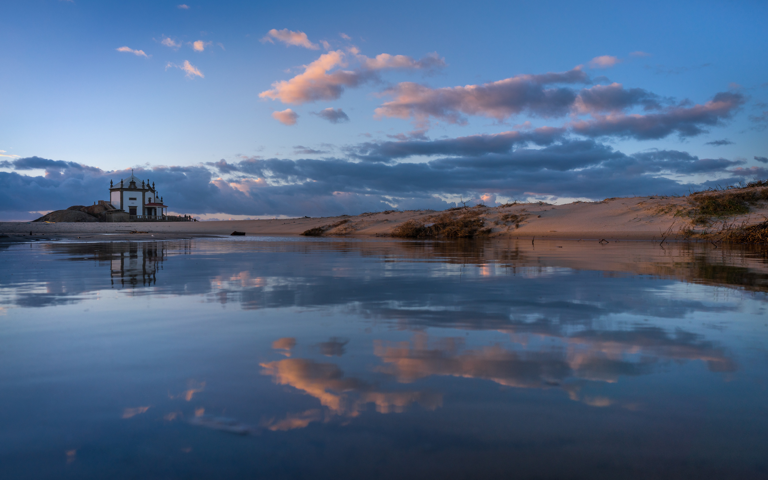 Облака отражаются в спокойной воде озера 