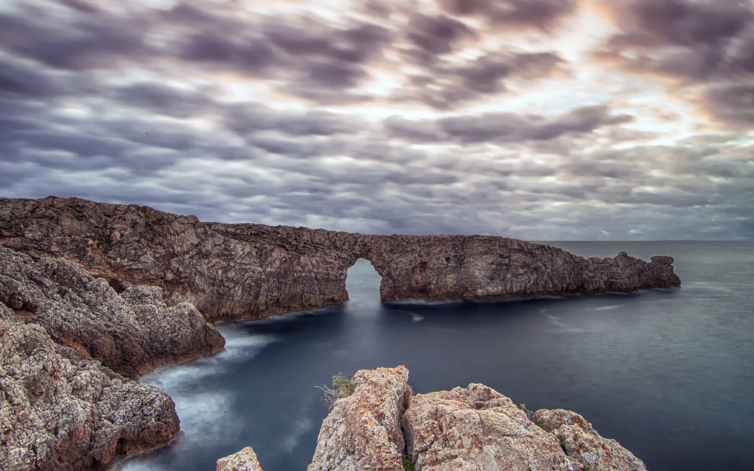 Арка в скале в море под пасмурным небом 