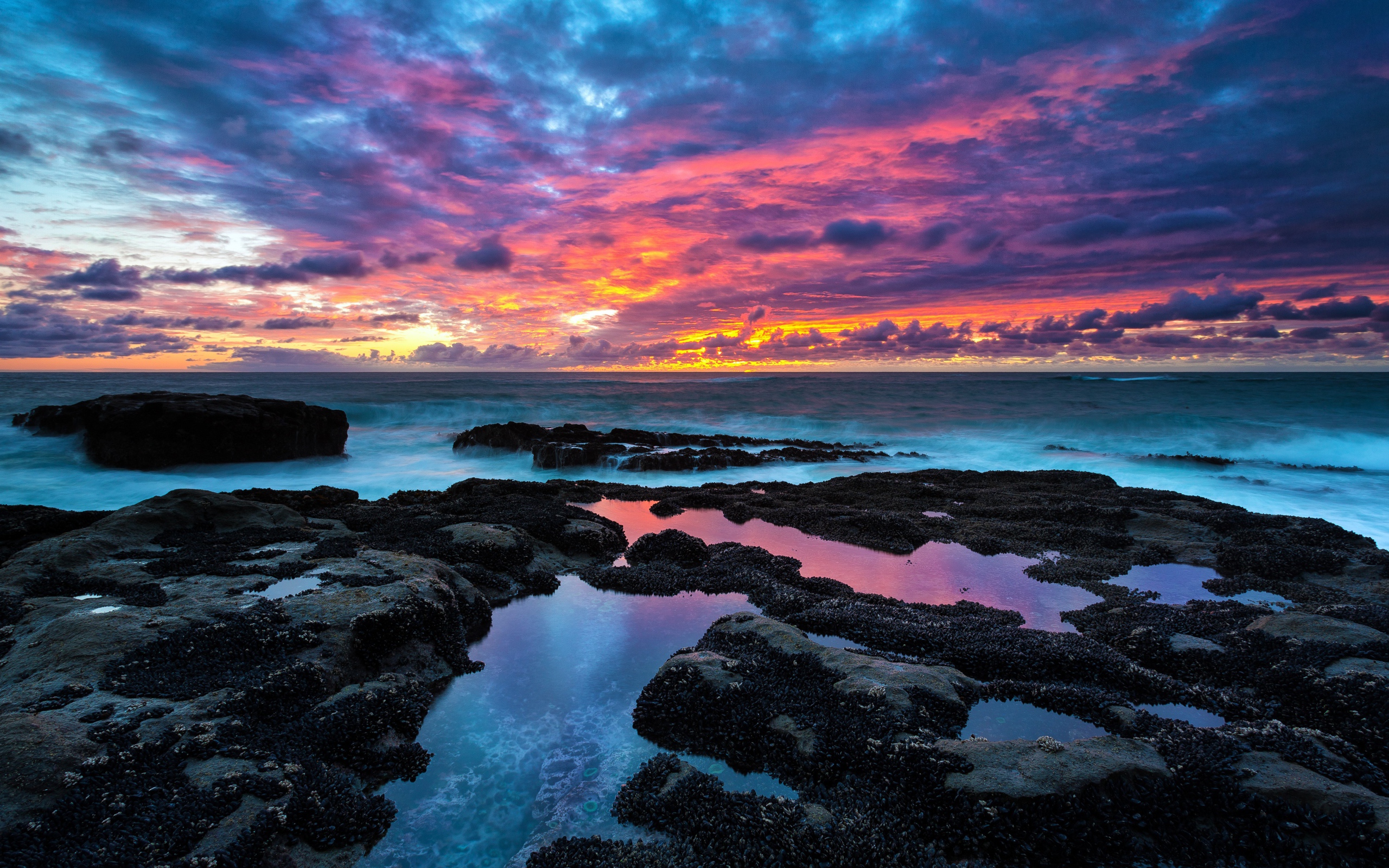 Восход яркого солнца над камнями в море