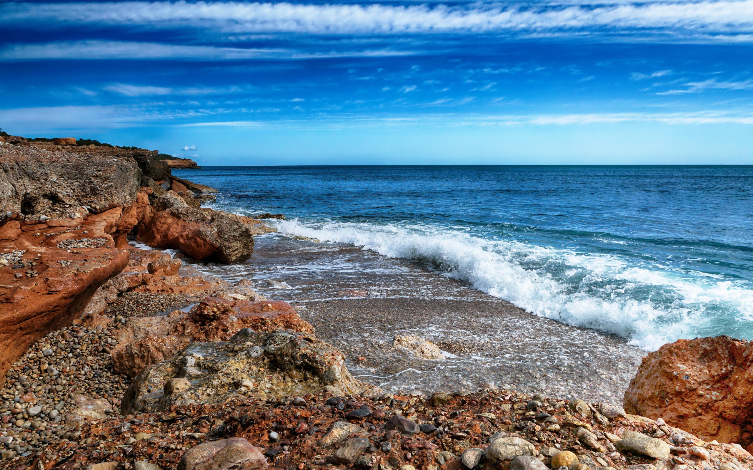 Белые волны на берегу моря с большими камнями под голубым небом
