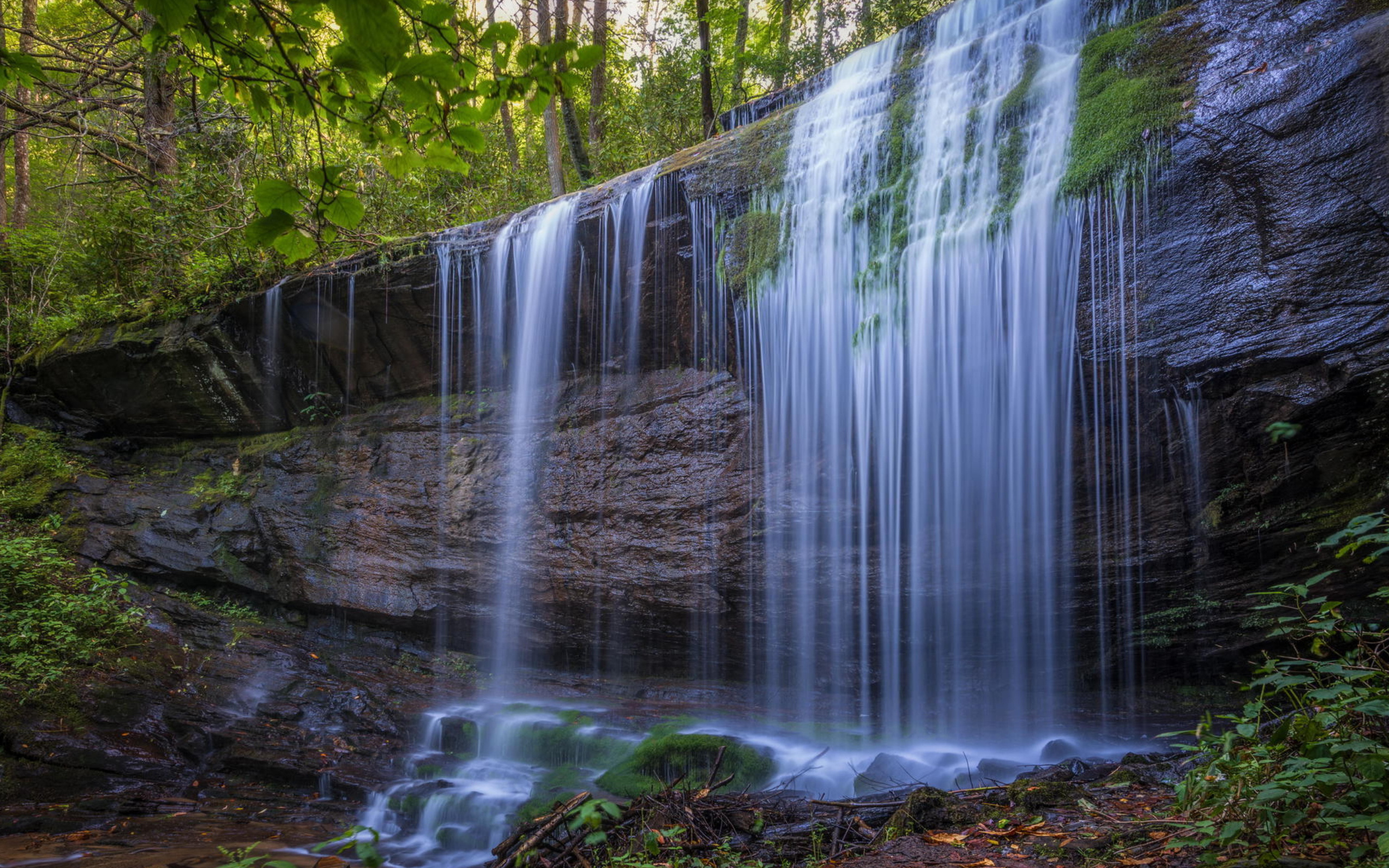 Холодная вода водопада стекает по мокрой скале