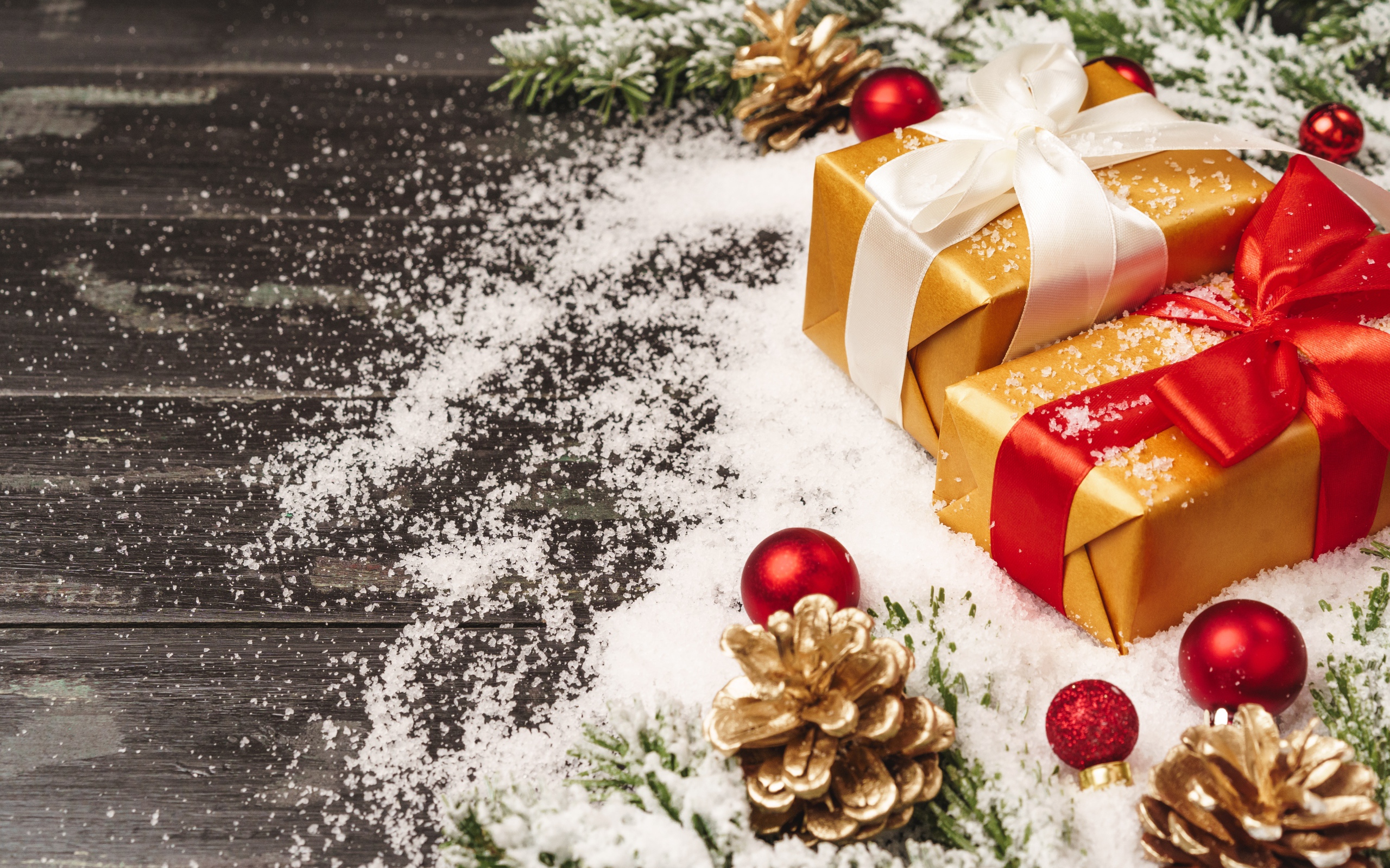 Два новогодних подарка на столе с еловыми ветками 