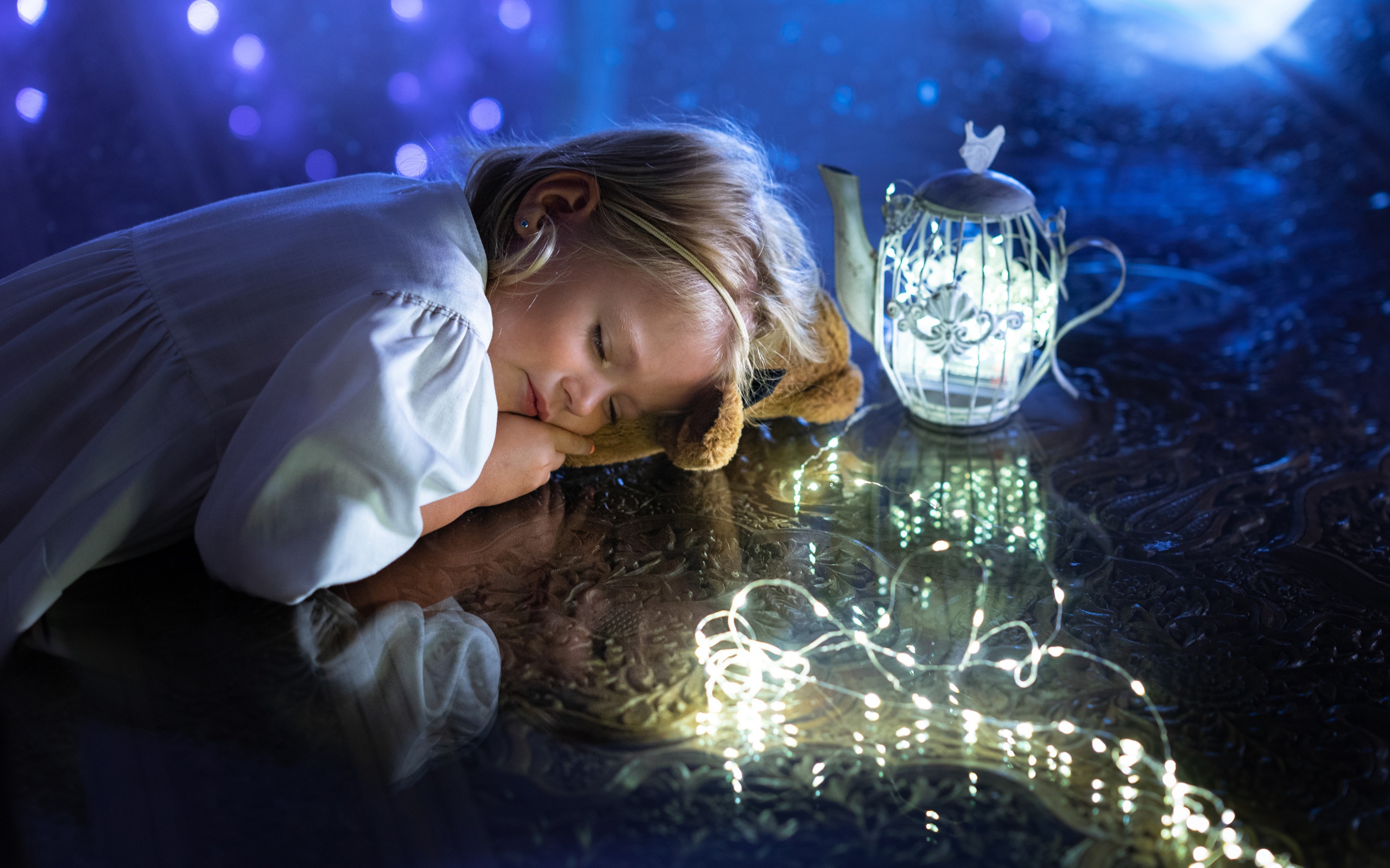 Милая маленькая девочка в белом платье спит на столе