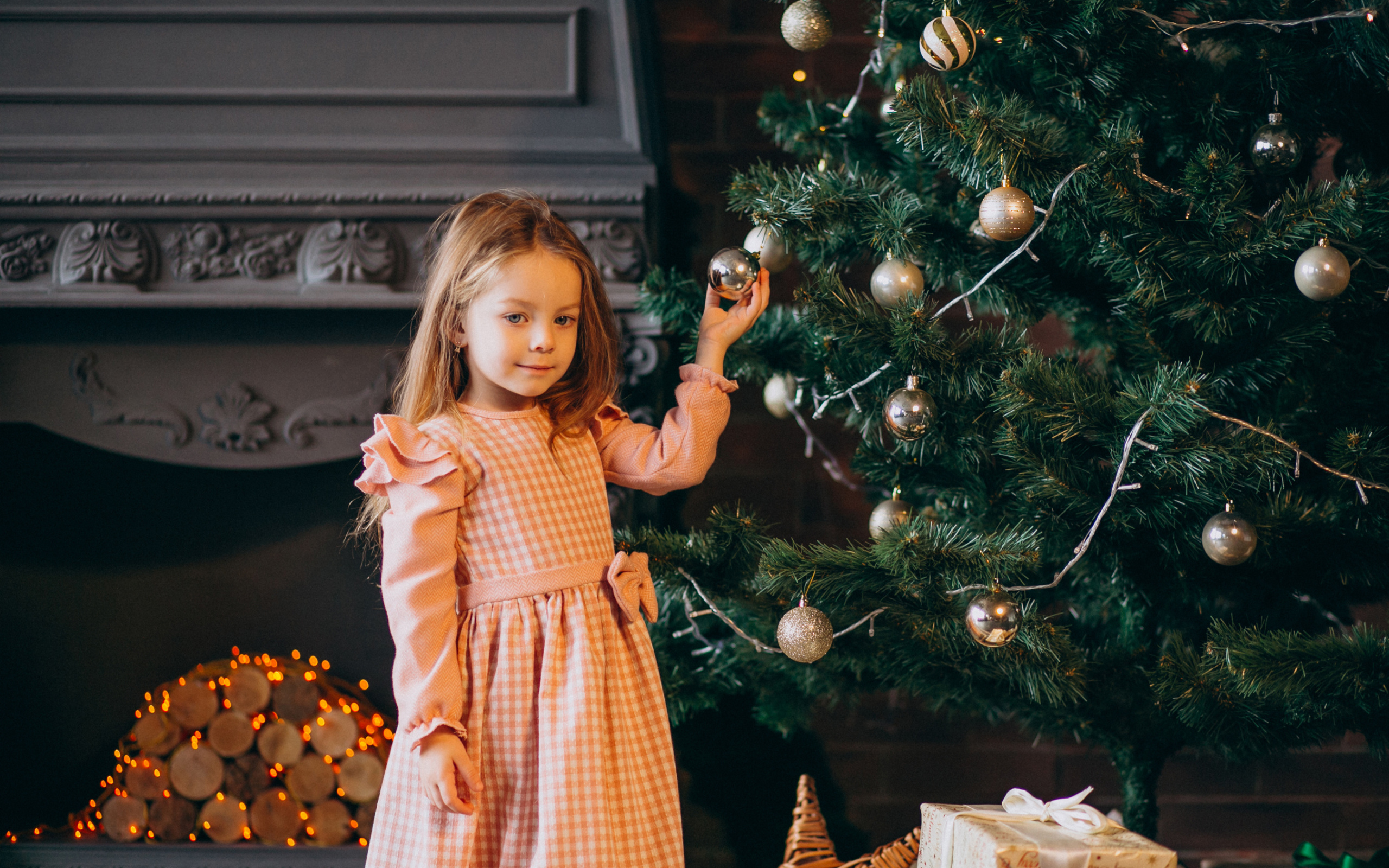 Милая маленькая девочка стоит у наряженной елки 
