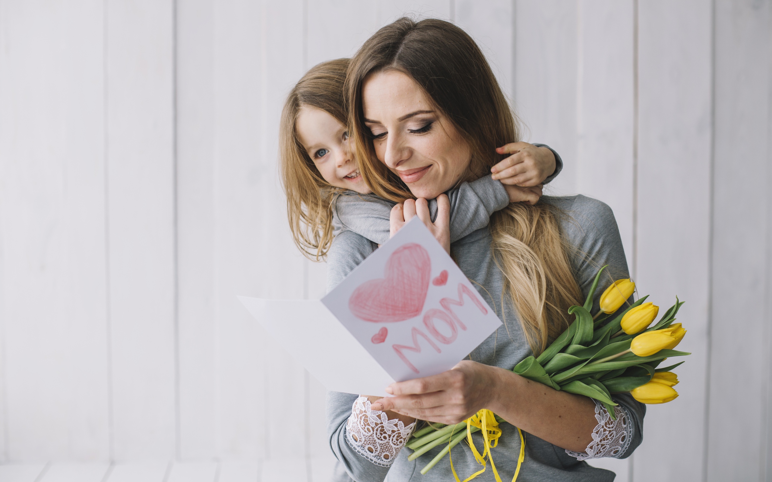 Маленькая девочка подарила маме открытку и букет тюльпанов