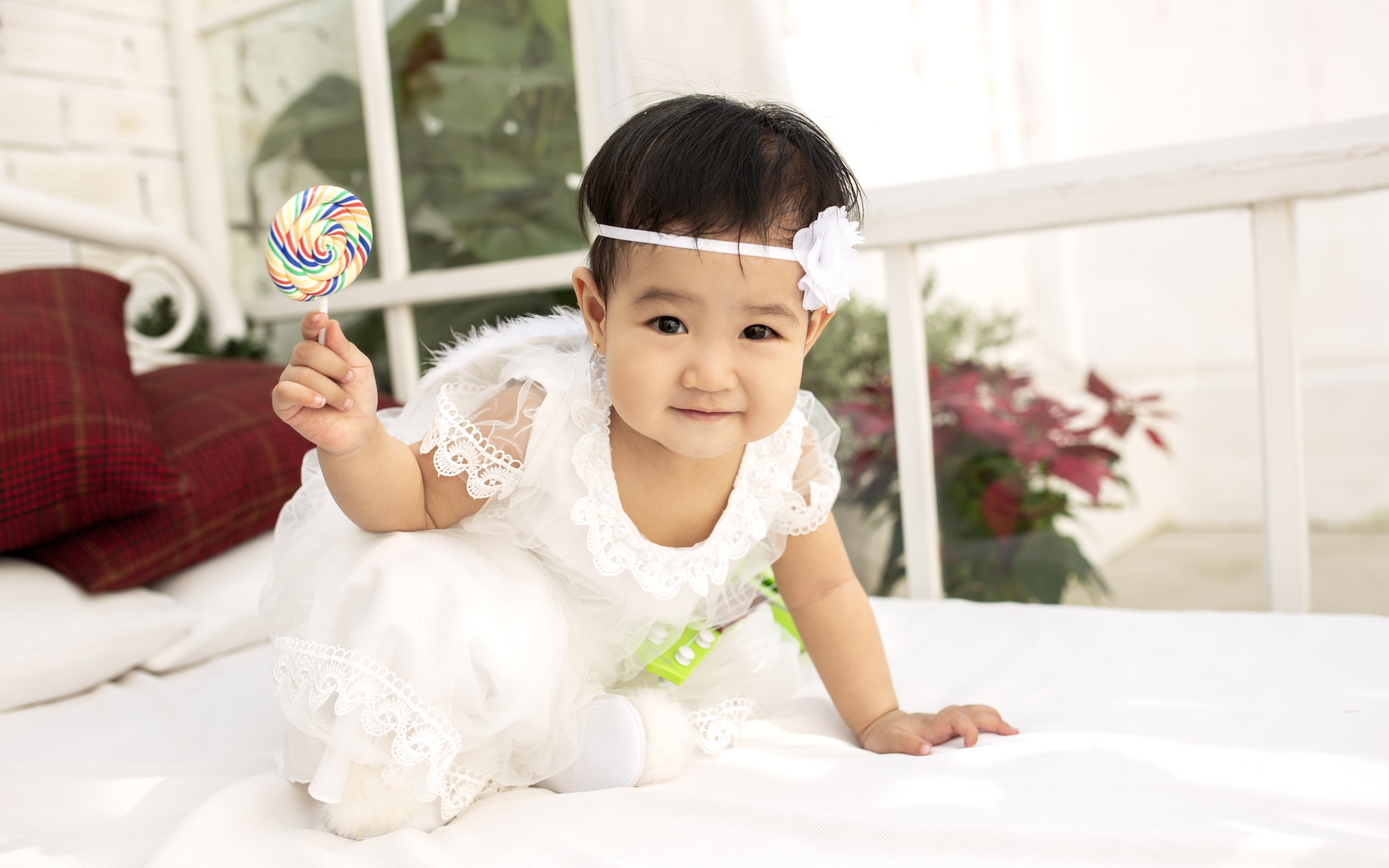 Маленькая девочка в белом платье с леденцом в руке