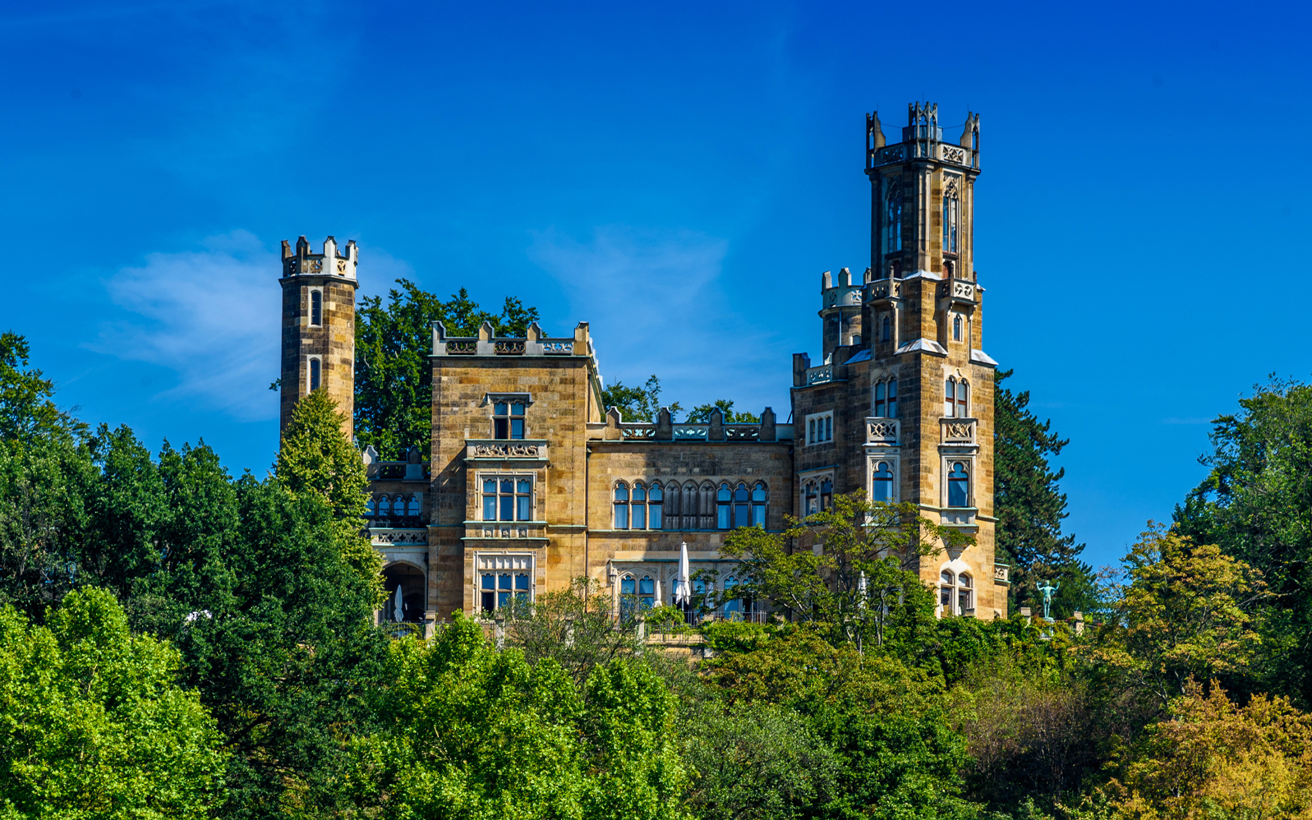 Старинный замок в зарослях деревьев на фоне голубого неба, Германия