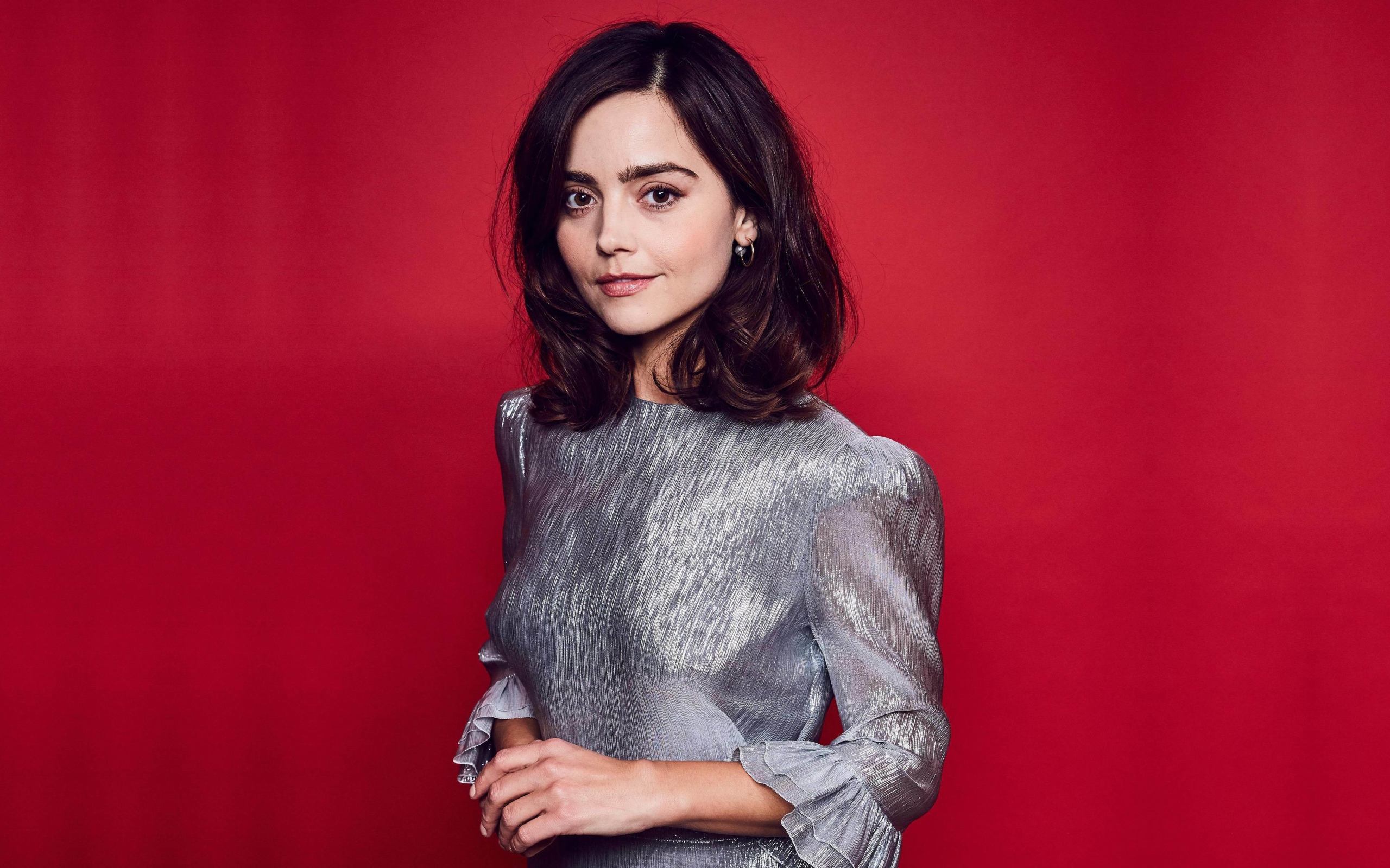 Американская актриса Дженна Коулман в сером платье на красном фоне