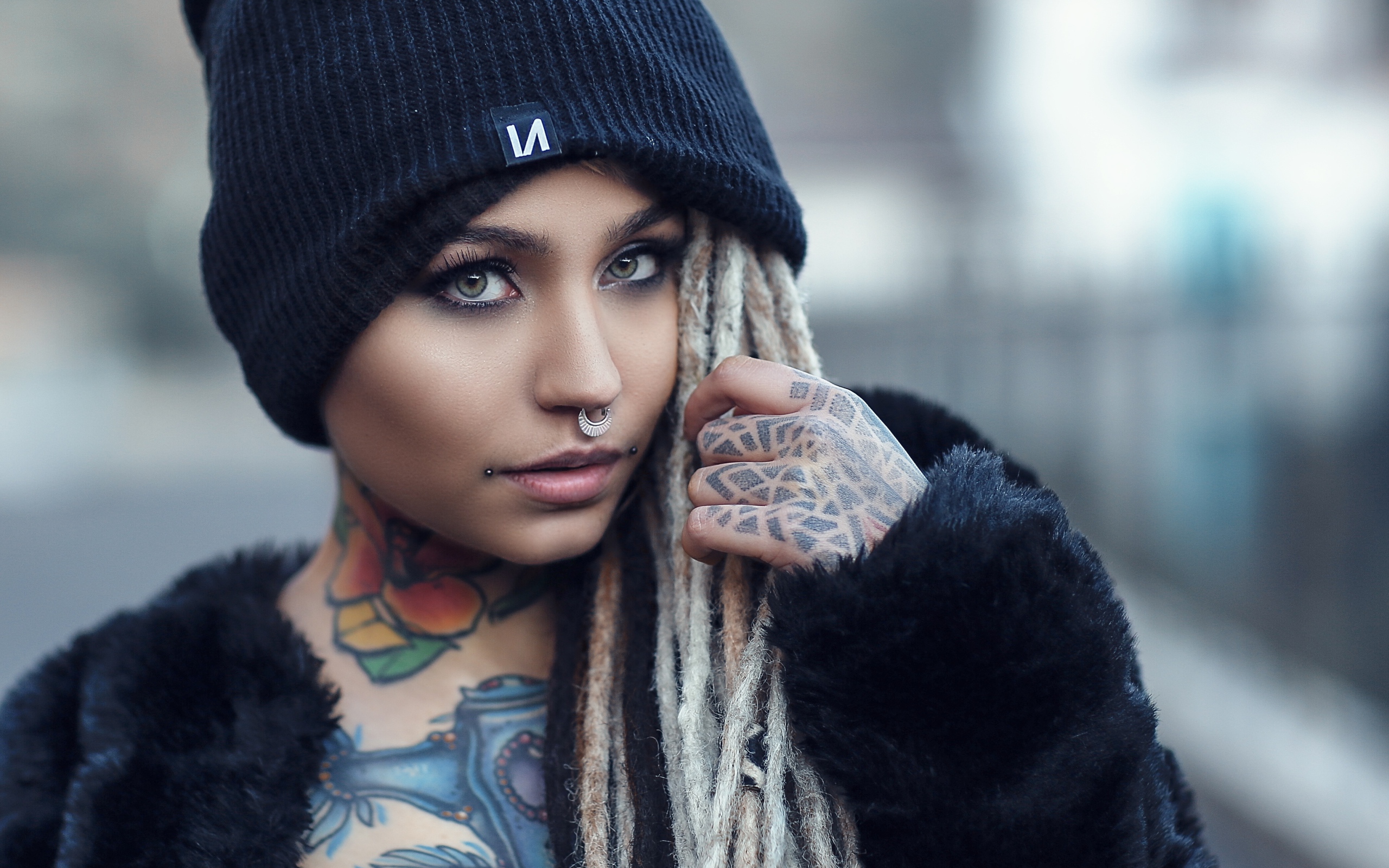 Красивая девушка в черной шапке с татуировками на теле 