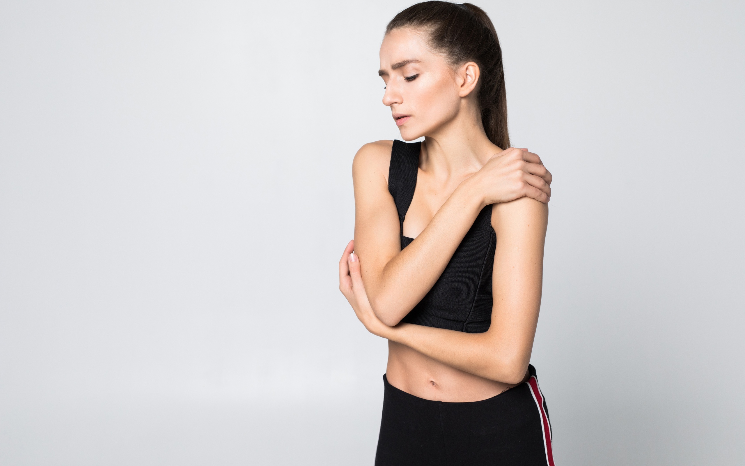 Скромная спортивная девушка на сером фоне