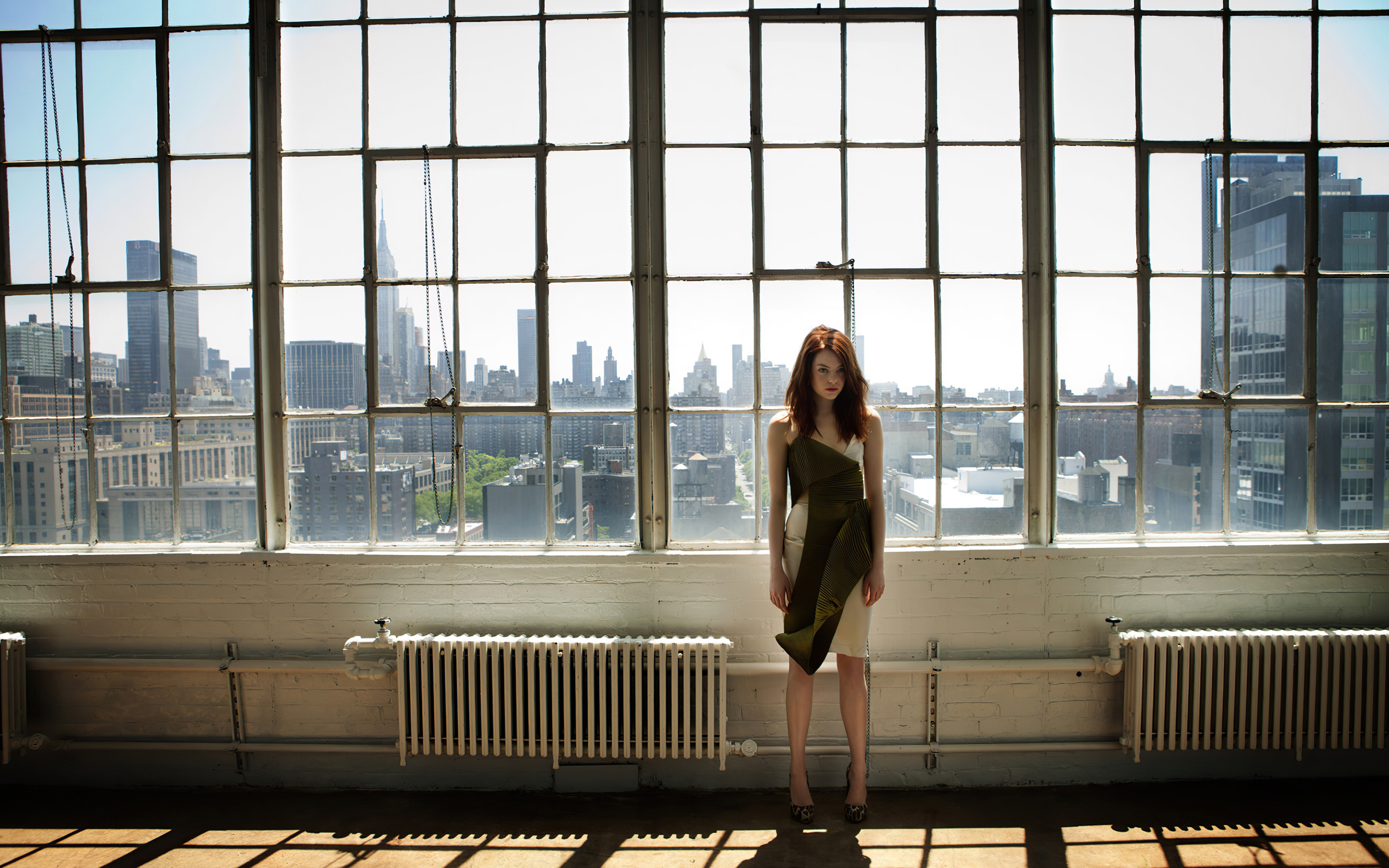 Популярная актриса Эмма Стоун стоит у большого окна