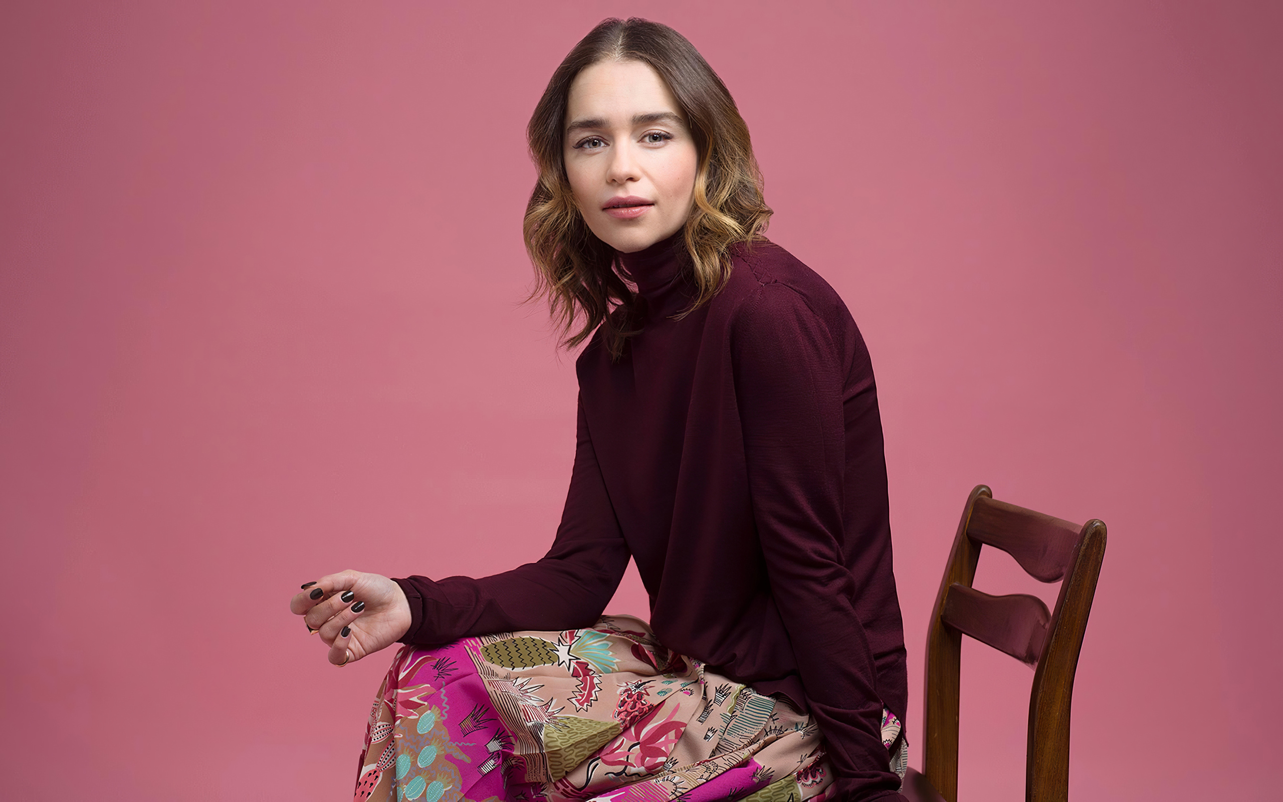 Молодая актриса Эмилия Кларк сидит на стуле