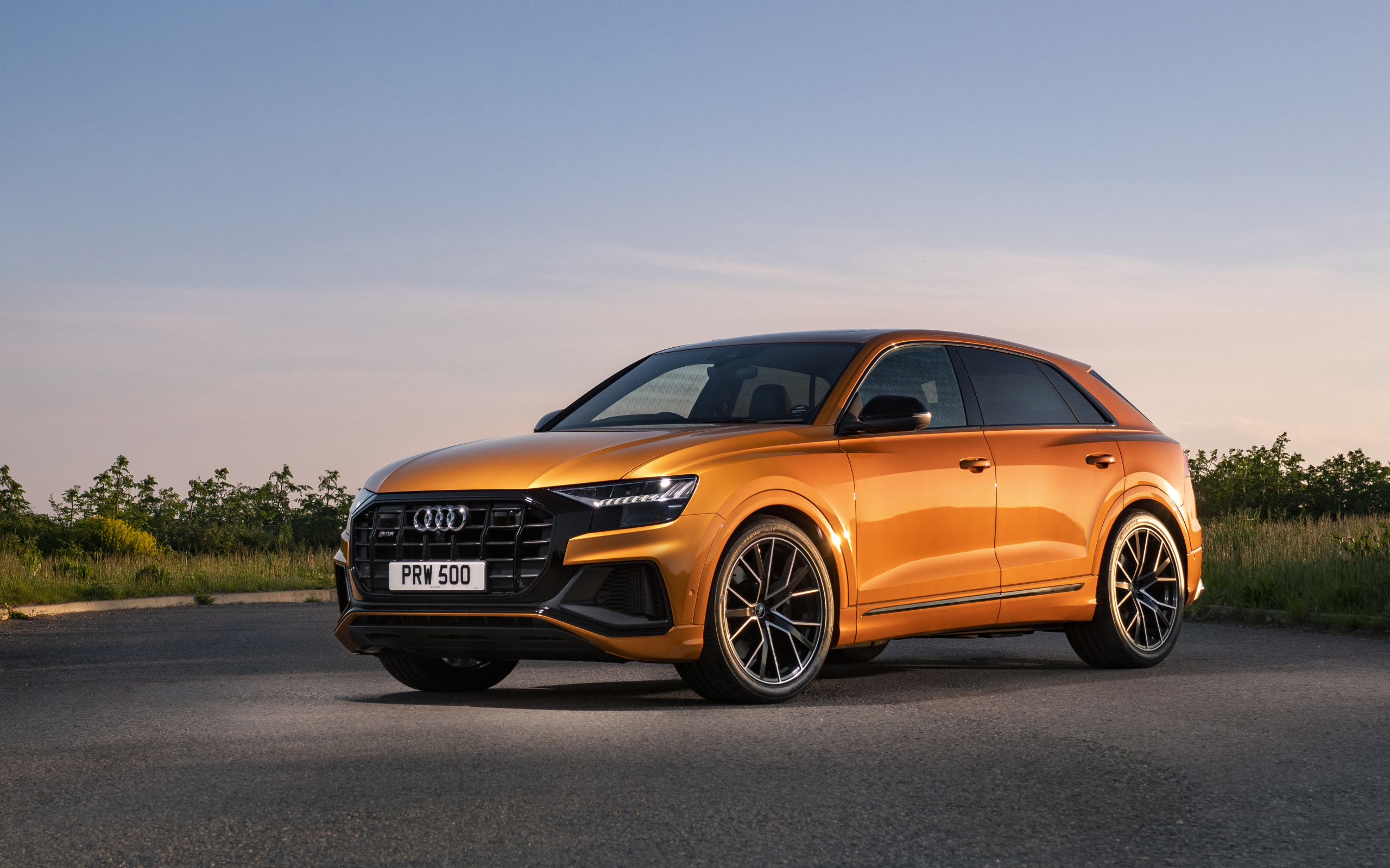 Оранжевый автомобиль Audi SQ8 TFSI 2021 года на фоне неба