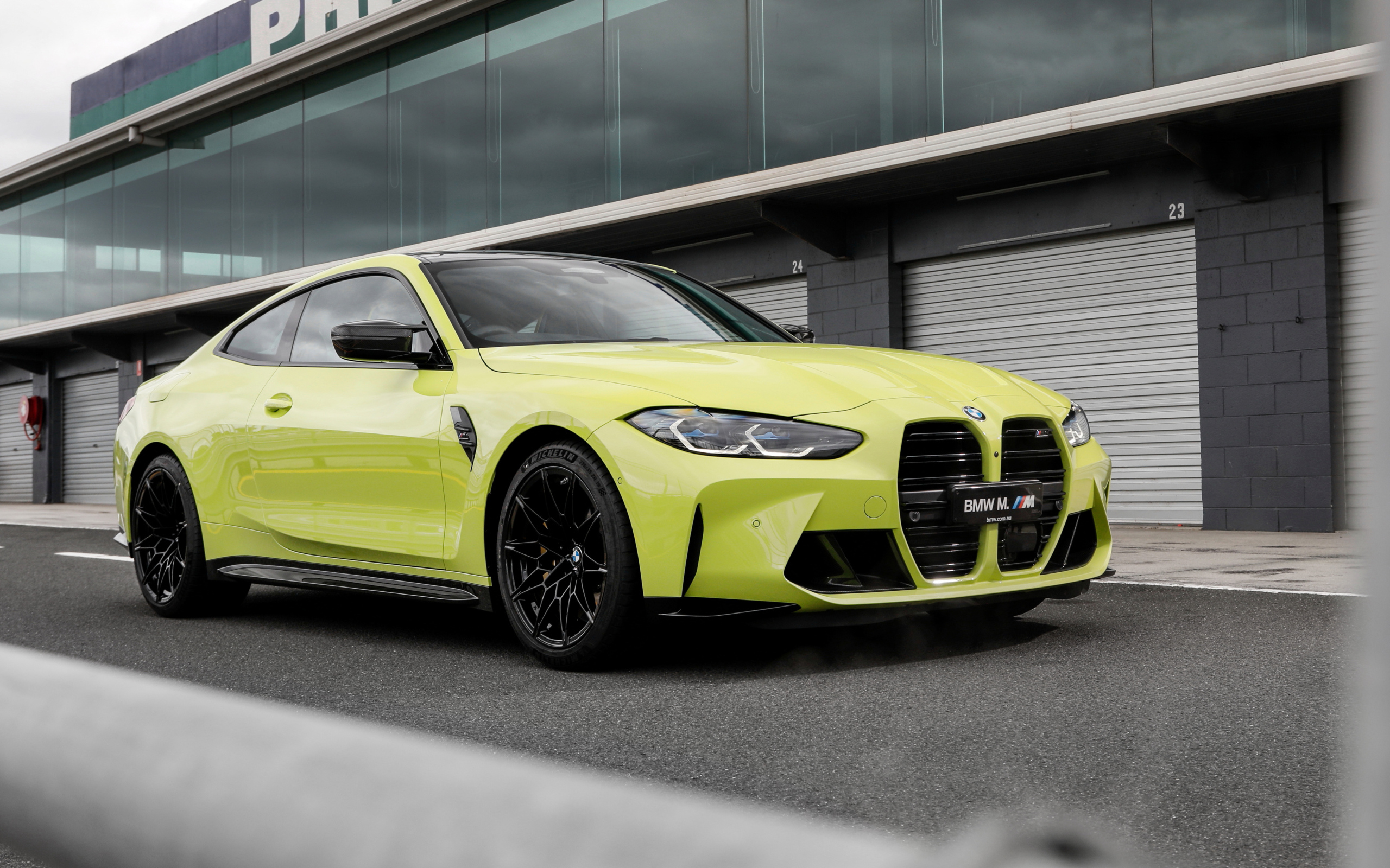 Желтый автомобиль BMW M4 Competition 2021 года у здания