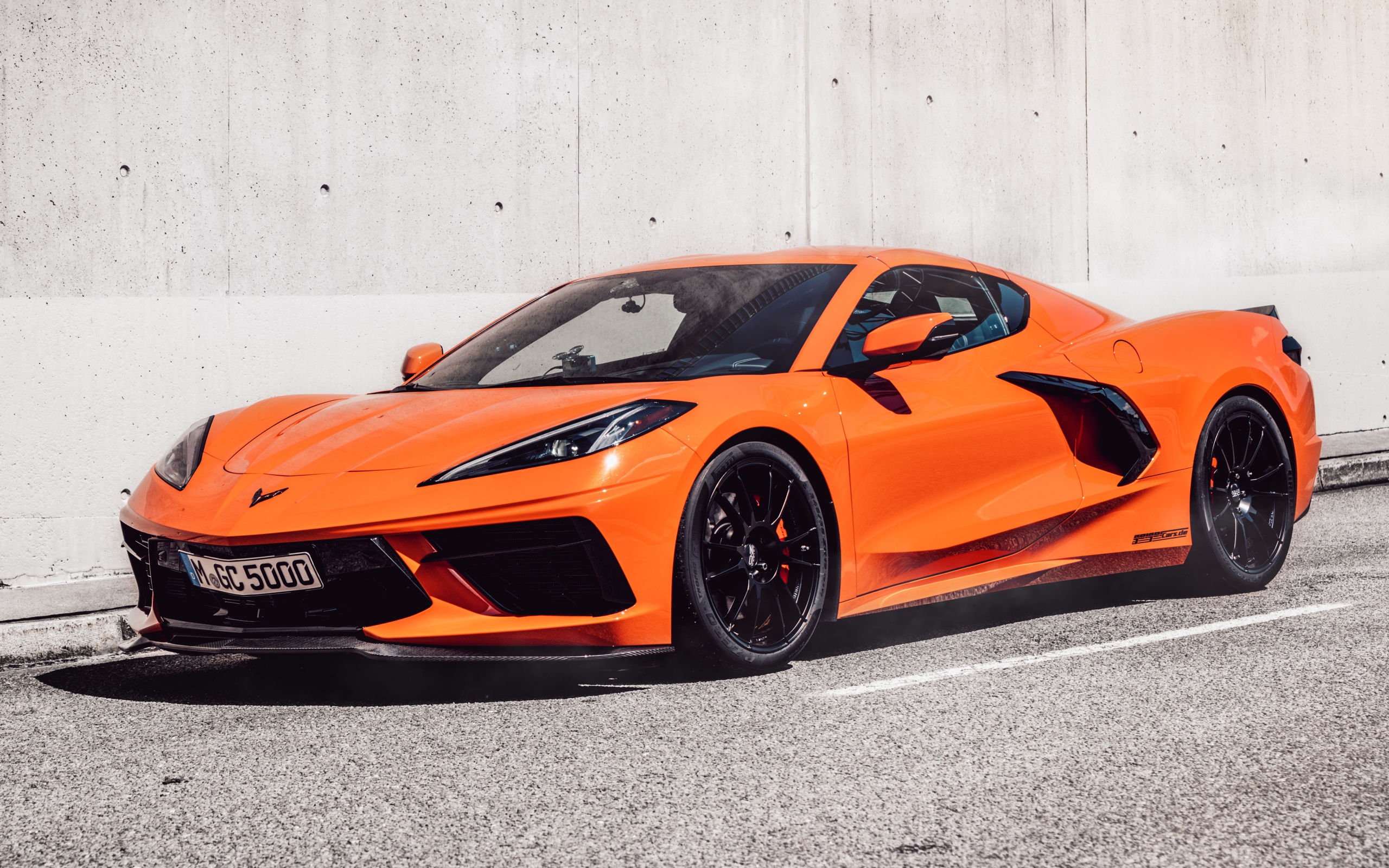 Оранжевый Chevrolet Corvette 2021 года на фоне серой стены