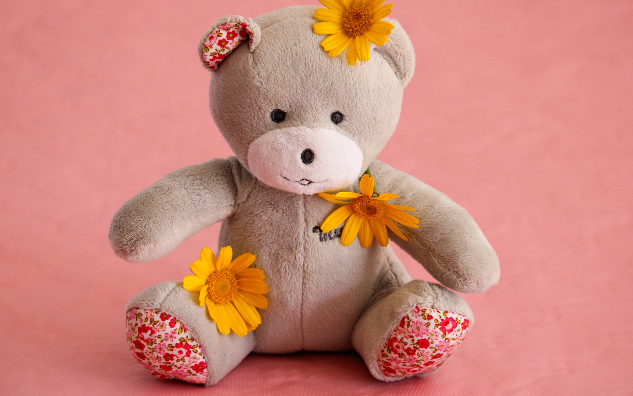 Красивый плюшевый мишка с цветами на розовом фоне