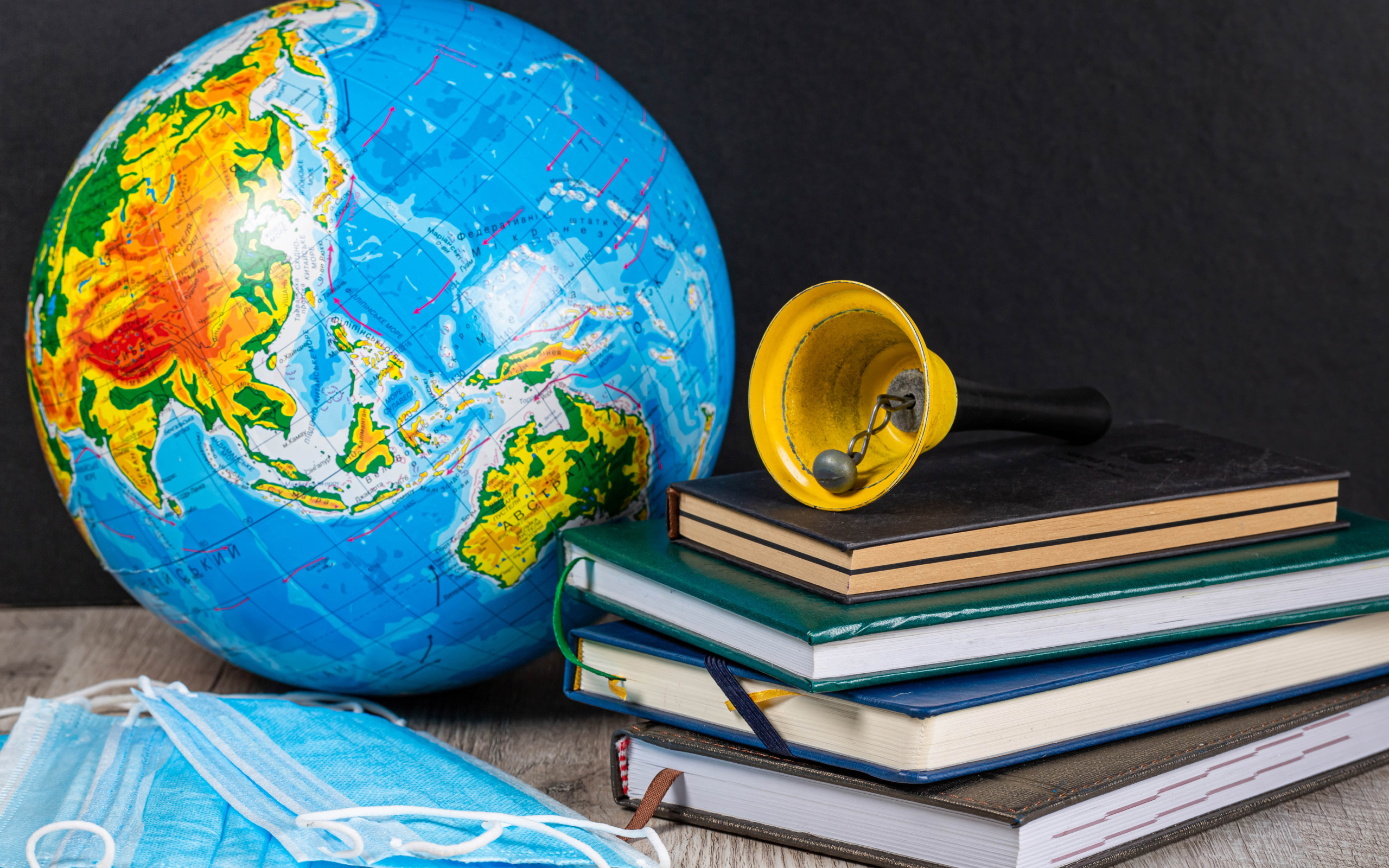 Глобус, книги, колокольчик и медицинские маски 