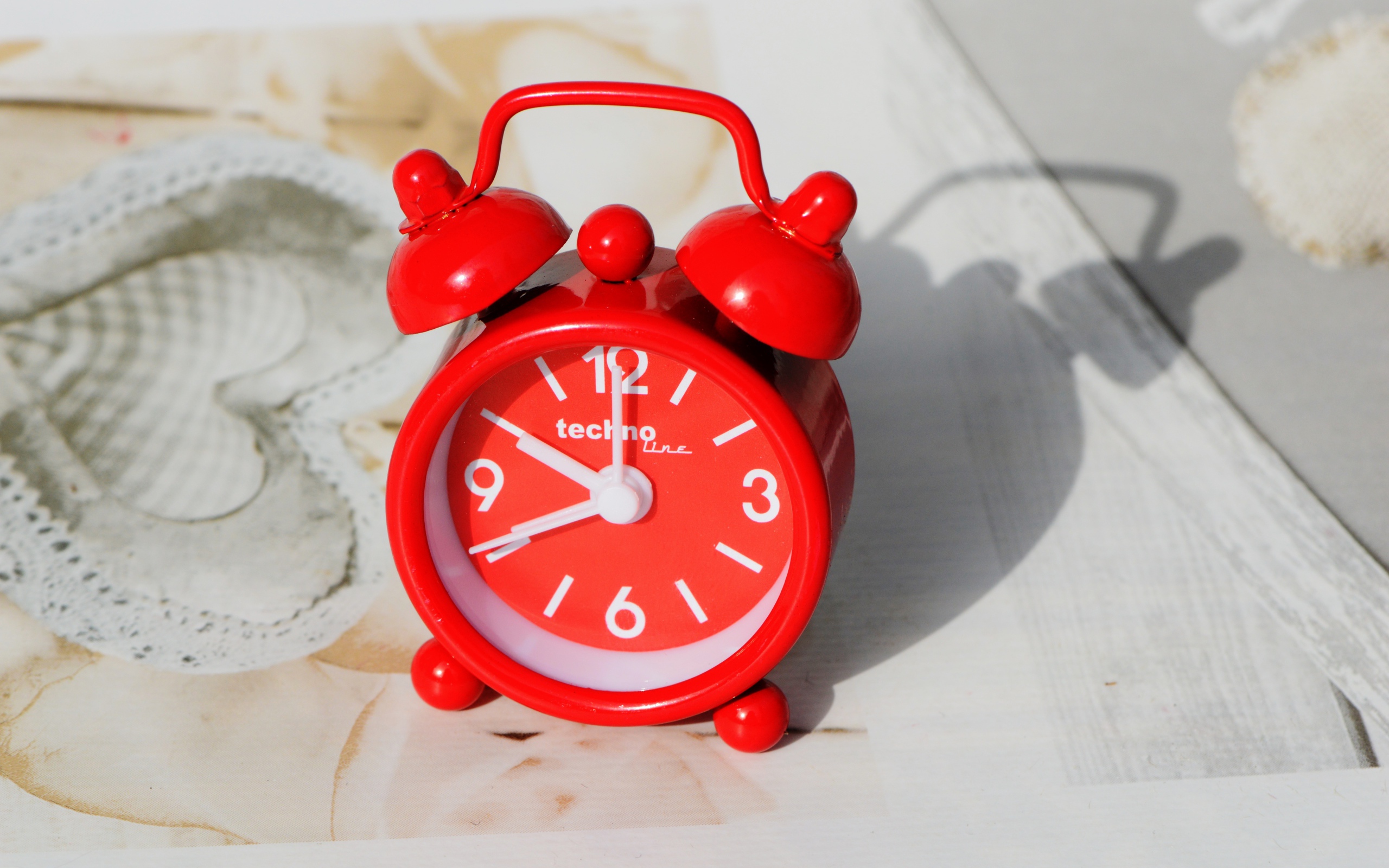 Маленький красный будильник стоит на столе 