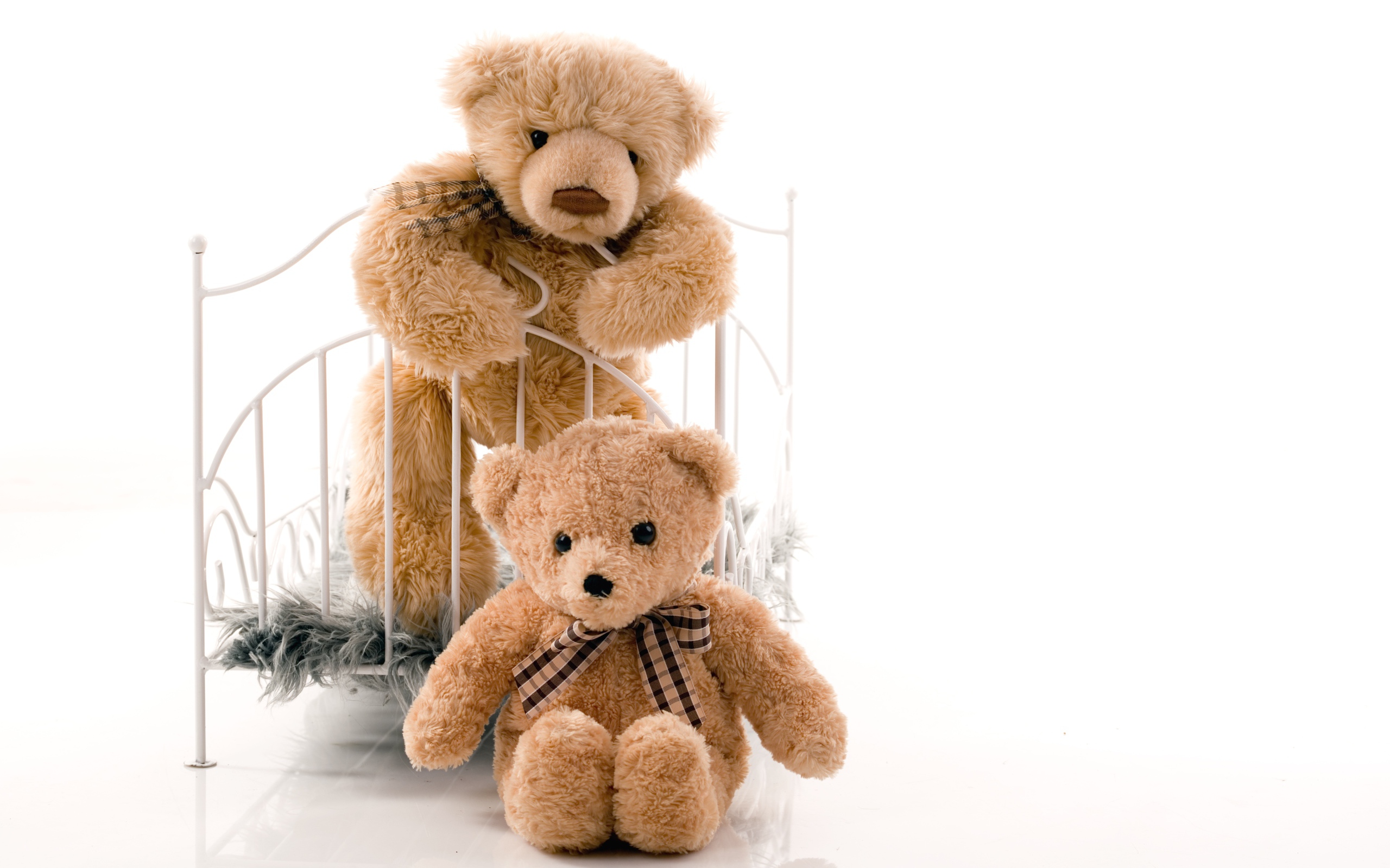 Два игрушечных медведя с кроватью на белом фоне 