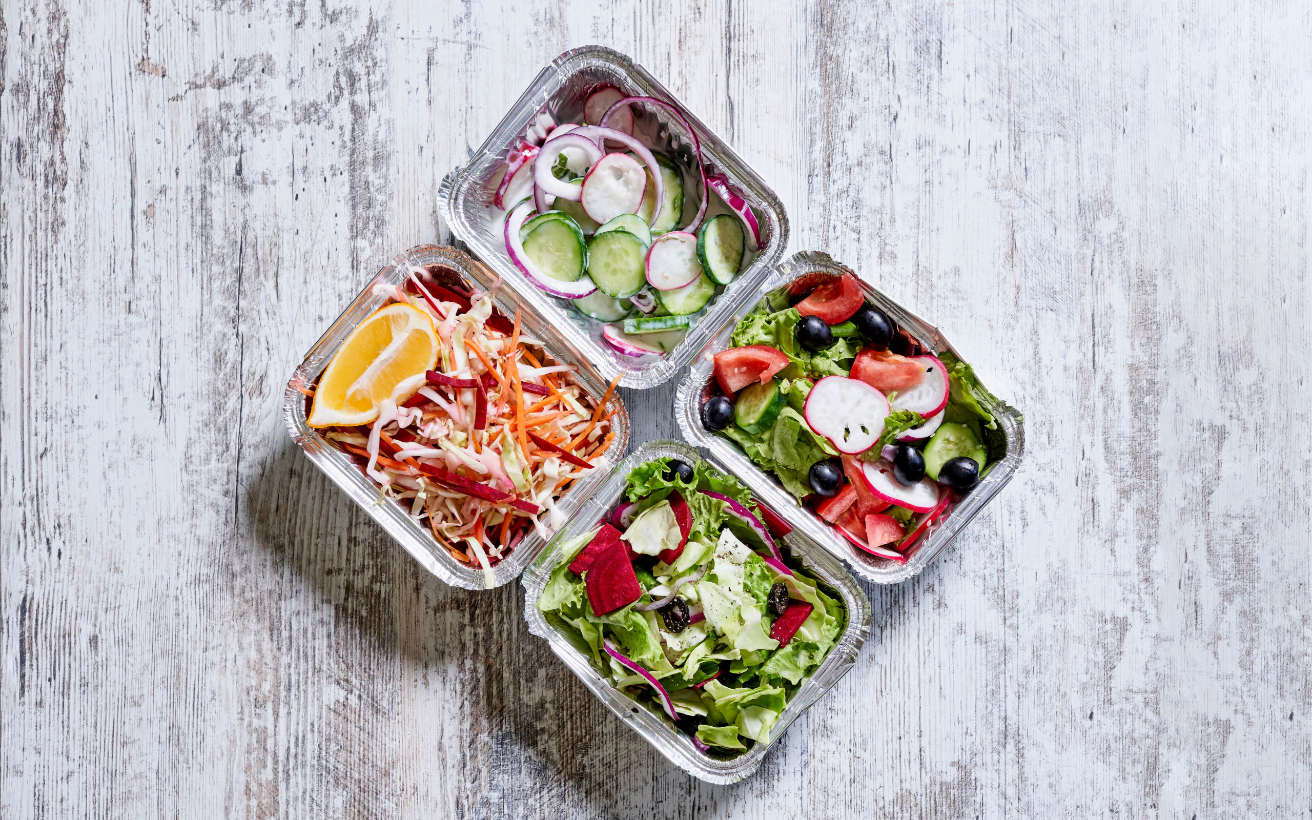 Разные овощные салаты в тарелках на сером столе 