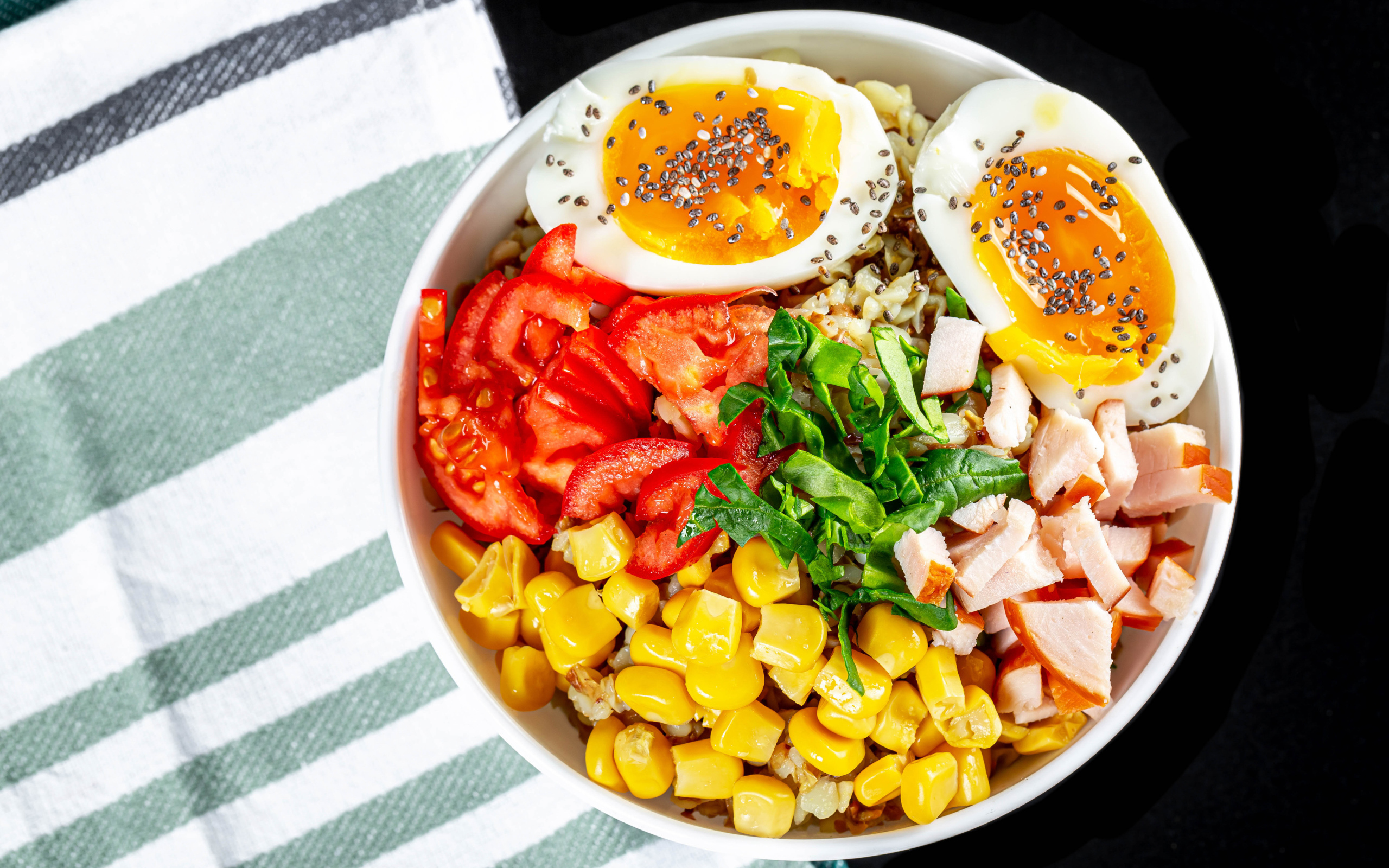 Каша в тарелке с помидорами, кукурузой, ветчиной и яйцом