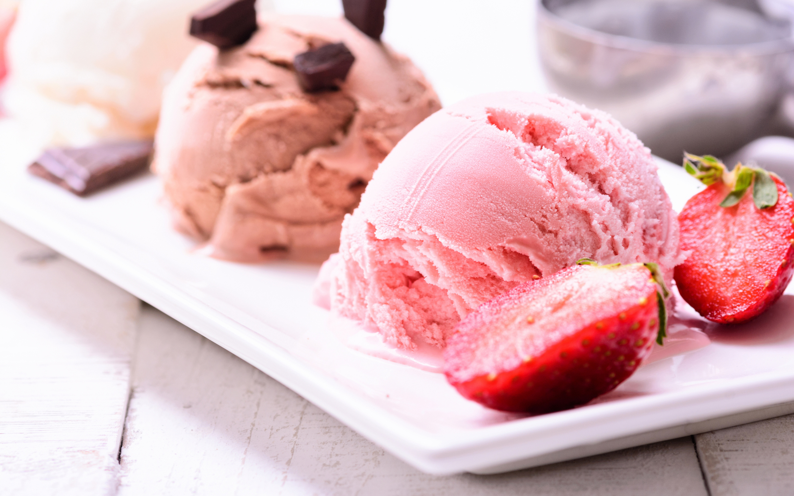 Шарики мороженого на большой белой тарелке с клубникой