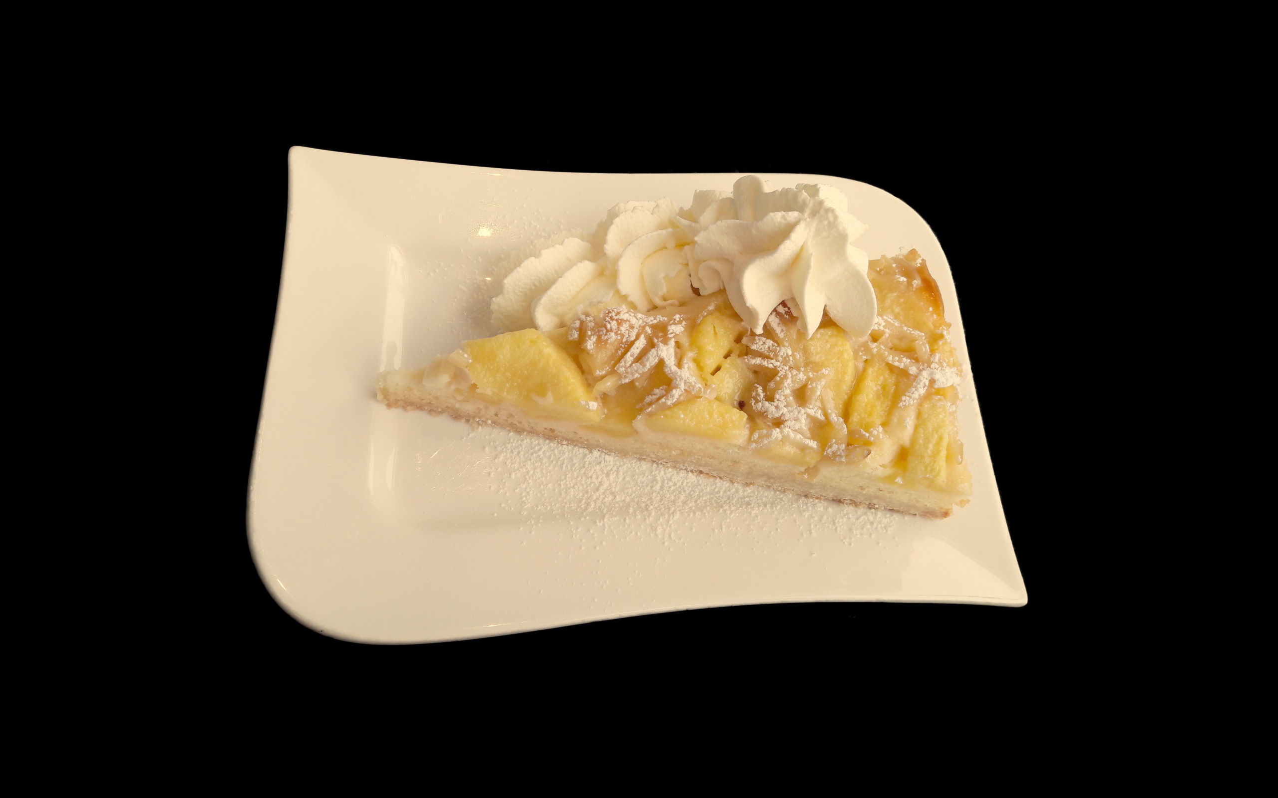 Кусок пирога с фруктами в белой тарелке на черном фоне