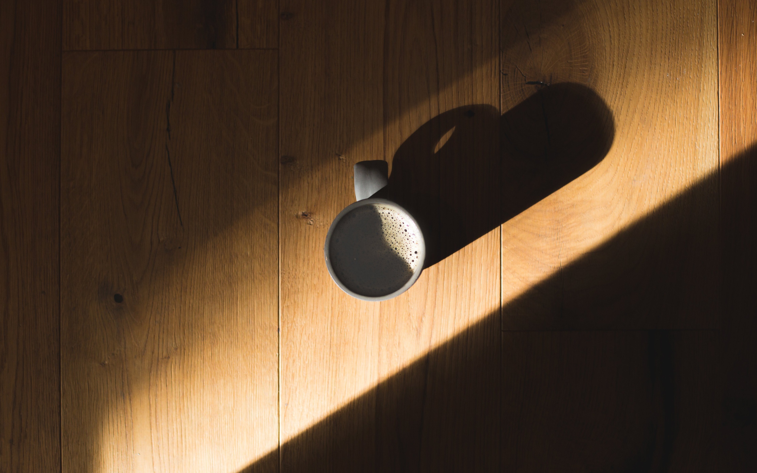 Чашка кофе стоит на столе в лучах солнца